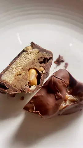 These home made snickers will make you fall in love 🖤 #fyp #foodtiktok #snickers  Snickers Ingredients  Nougat base: blend together & freeze base before adding caramel layer    2 cups rolled oats 1 cup almond flour or coconut flour 2 tBsp maple syrup 3 tBsp coconut oil 1/2 tsp salt 1/2 cup oat milk or your favourite milk Caramel layer: blend and add to base & freeze again  12 dates I used medjol dates 3 tBsp peanut butter 1/3 cup melted coconut oil 1/4 cup maple syrup 1 tsp vanilla extrac▢  1/2 tsp salt 3 tBsp peanuts (layer on top of caramel layer)  Coating: melt chocolate & coat  ~1 cup dark chocolate or milk chocolate if you prefer 