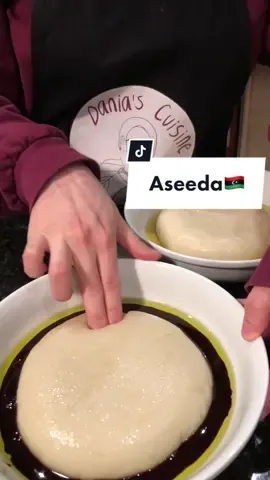 Libyan aseeda🇱🇾 This is not the only way to make aseeda, every Libyan household differs. Helpful tip: use a stand mixer instead of manual mixing. I wanted to show the manual method for tradition’s sake. Aseeda to serve 3 people:  -4 cups of water -1/2 tsp salt -1 tbsp olive oil -3 cups flour -olive oil and honey or date syrup (to serve) Heat up the water, salt, and olive oil together in a pot until it boils. Set about a cup of this aside before quickly mixing all-purpose flour into the pot. Mix this very well, this will require some arm strength; you can do this part off the heat. Then, add the portion of water you set aside and let this cook on low heat for 10 minutes. After the 10 minutes are up, whip the aseeda one more time. The mixture is now ready. To serve, add olive oil to each plate and portion out the aseeda. Shape it into a round disk, you can dip your hand in water to help. Then top with more olive oil, and honey or date syrup and enjoy! #libyanfood #libya #libyan #northafrican #african #AfricanFood #arab #🇱🇾 #Recipe #food #Foodie #dessert #breakfast #foodinspo