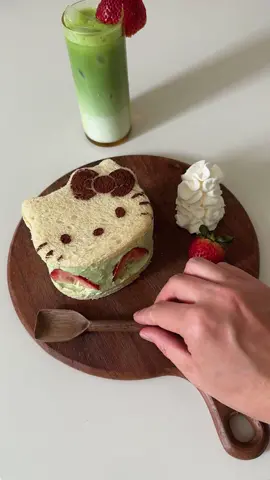 make a #hellokitty fruit sando with me 🍓🍵 recipe 2 milk bread slices 1 cup heavy cream 2 tsp matcha powder 1/4 cup granulated sugar 3-4 strawberries cut in half Cocoa powder for decoration 1. Cut the 2 milk bread slices with the Hello Kitty mold 2. Whip the heavy cream, matcha powder, and granulated sugar until fluffy 3. Using the ring, assemble the sandwich with one slice of bread, a layer of cream, strawberry slices, another layer of cream, and the second slice of bread 4. Refrigerate for 30 minutes 5. Sprinkle cocoa powder carefully over Hello Kitty face liner 