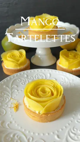 🥭 Mango Tartelletes  Recipe 👩🏻‍🍳 Mango tartelletes are an exotic temptation that will make every dessert lover’s heart skip a beat. Ingredients for approximately 7-8 tartlets (8 cm diameter): 🥛 For the tart crust: - 250 g flour - 125 g cold butter - 40 g powdered sugar - 1 cold egg - Pinch of salt - 2 tablespoons ice-cold water - 1 teaspoon vanilla extract 🥭 For the filling : - 125 g mascarpone - 125 g ricotta - 100 ml cream - Half a ripe mango, pureed - 1 heaping tablespoon powdered sugar - Juice of half a lemon For decoration: - 2 large ripe mangoes Instructions: Knead the flour, cold butter, powdered sugar, cold egg, pinch of salt, ice-cold water, and vanilla extract together to form a smooth dough. Allow the dough to rest in the refrigerator for 1-2 hours to make it easier to roll out later. While the dough is resting, prepare the irresistible filling. Whip together with a mixer the mascarpone, ricotta, and cream until creamy, then add the pureed mango, powdered sugar, and freshly squeezed lemon juice. Stir everything together well until you achieve a creamy and fruity consistency. Remove the dough from the refrigerator and roll it out on a lightly floured surface and place them in the tartlet molds. To ensure even baking, cover the tartlet bottoms with parchment paper and fill them with baking beans or other weights. This process, known as „blind baking,“ will help the crust bake evenly and become delightfully crispy. Bake the tartlets in a preheated oven at 160 degrees Celsius for approximately 20-25 minutes until blind-baked. After baking, remove the parchment paper and baking beans and allow the tartelletes crusts to cool completely. Take the prepared filling out of the refrigerator and fill the tartlet shells with it. Smooth the surface to ensure an even distribution. Peel a ripe mango and slice it into thin pieces. Shape the mango slices into delicate roses and place them on top of the tartlets as an impressive decoration. These beautiful mango roses give the tartlets an elegant look. These delightful treats will undoubtedly be the highlight of your next coffee table or celebration. Enjoy! 👩🏻‍🍳🥭🌹 