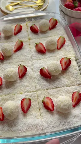 RAFFAELLO CAKE #raffaello #cake #coconut #Recipe #food #tiktokfood #foodtiktok #viral #trending CAKE BATTER 3 eggs (m) 100 g granulated sugar 8 g vanilla sugar  100 ml milk 75 g unsalted butter 65 ml sunflower oil 175 g flour 10 g baking powder   FILLING 400 ml milk 75 g granulated sugar 8 g vanilla sugar  50 g cornstarch 150 ml whipping cream 100 g white chocolate 40 g grated coconut   MILK MIXTURE 250 ml milk 75 g granulated sugar   GARNISH Grated coconut Strawberries   Melt the unsalted butter in a saucepan over low heat. Let it cool.   Break the eggs into a bowl. Add the sugar and vanilla sugar, and mix for 1 minute. Add the milk, melted butter, and sunflower oil. Mix until smooth. Sift the flour and baking powder into the bowl and mix until combined.   Transfer half of the cake batter to an oven dish or cake pan. Place the cake in a preheated oven at 175°C and bake for 10 minutes.   Heat the milk in a frying pan together with the sugar, vanilla sugar, and cornstarch over medium-low heat. Stir continuously. When the mixture starts to thicken, add the whipping cream. Mix well. Remove the pan from the heat. Add the crushed white chocolate and let it sit for 1 minute. Stir until fully dissolved. Add the grated coconut and mix well. Divide the coconut mixture in half and let it cool.   Spread half of the coconut mixture over the cake, followed by the remaining cake batter.   Place the coconut cake back in the preheated oven at 175°C and bake for 30 minutes. Keep an eye on the baking time, as every oven is different.   In a saucepan, bring the milk (250 ml) and sugar (75 g) to a boil.   Pour the milk mixture over the coconut cake and let it soak. Then let it cool.   Evenly distribute the remaining coconut mixture (250 g) over the coconut cake and sprinkle some grated coconut on top.   Tips: Garnish the Raffaello cake with baked/roasted almonds. Add sugar according to taste.    