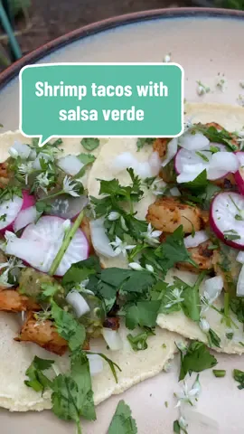 Chili lime shrimp tacos with salsa verde 💚 My favorite thing to make with tomatillos! Some salsa verde, with some delicious homemade shrimp tacos to put it on!  To make the shrimp: Season 1lb of shrimp with zest of one lime, juice of two limes, paprika, cumin, spicy pepper powder, salt and pepper to taste  Grill shrimp on cast iron skillet over medium high heat, cooking 3 minutes per side.  To make the salsa verde: Roast tomatillos in a roasting pan, along with one onion, one bulb of garlic, and jalapeños and Serranos to taste. I used 2 jalapeños and three Serranos and it was maybe 6/10 spicy. Sprinkle with salt. All of this is to taste. Can use as much or as little as you’d like. Roast at 450 until charred. Transfer to blender or food processor and add lime juice and cilantro to taste. Add salt to taste.  To make tortillas: 2 cups masa flour 1/2 tsp salt Add water until you can form a disk without the dough cracking. Press with tortilla press. Cook 15 seconds on a cast iron skillet over medium high heat. Then flip. Cool 90 seconds. Then flip. It should inflate at the last flip. It’s done!  Serve tacos with shrimp, top with salsa verde, onion, radish, cilantro, and chive blossoms. Enjoy! #gardentotable #gardentok #salsaverde #gardenharvest #gardeningtiktok #cottagecore #farmtotable #urbangardening 