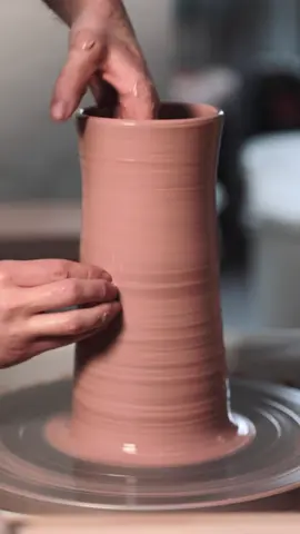 Throwing a simple vase this time, angular, but only slightly. Centred, opened up, the base compressed and then the walls are drawn up. This beginning process of centring and forming the base is when the foundations for the rest of the pot are set. Poor foundations, such as badly centred clay or a base left too thick or too thin, may only lead to complications down the line and a harder pot to throw.     I do rush it, sometimes, with pots that I know I can get away with throwing quickly and not perfectly accurately. Mugs and bowls mainly, as there is a way of lifting the clay up and centring an undulating rim as the soft clay is compressed from the top whilst being drawn up by my hands. I also don’t mind if there’s a minute irregularity in the shape as normally, I’ll be able to fix it at the leather hard stage. This isn’t every pot of course, but sometimes there’s a slightly more stubborn lump of clay to centre and pockets of air to contend with.    This changes for larger pots, or for pieces with galleries for lids or if they have complex, angular shapes. In these instances, I work more slowly and carefully, setting the foundations properly, all the way back to thoroughly spiral wedging the lump of clay. Whereas again, if I’m throwing 100 mugs or bowls, there’s a high chance that not every ball of clay will be properly wedged.    Some throwers work steadily and slowly, whereas others throw in a miraculous way where the pot feels like it’s on the verge of collapse whilst being rapidly drawn into existence. One such potter is Francis Power, a thrower I watched in Ireland during my training on the DCCoI Ceramics Skills & Design Training Course. I don’t think I’ve ever been as transfixed as watching him work and my vase in this video is thrown at a snail’s pace in comparison.    #vase #wheelthrownpottery #ceramics #handmade #pottery #asmr   