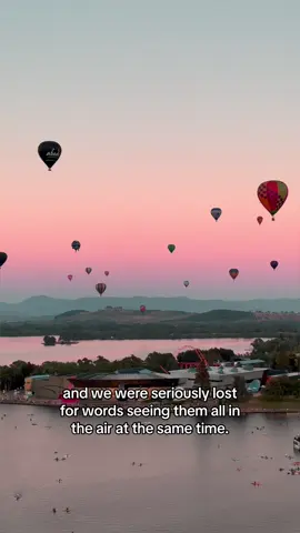 Yes, this is in Australia! 🤯 The sight of #Canberra's balloon-filled skies as part of the #CanberraBalloonSpectacular is seriously mid-blowing. Around 40 hot air balloons are currently soaring over the city at sunrise each morning, a surreal sight you can catch for yourself until 17 March 🎈. It's well worth the early morning start to catch the dream-like vibe this event delivers (followed by a delicious coffee, of course!) 📍: #Canberra, #AustraliasCapitalTerritory  #SeeAustralia #ComeAndSayGDay #Australia #Travel #TravelAustralia #TravelTheWorld #Adventure #BucketList.  ID: Colourful hot air balloons take off as crowds watch on below, then float gracefully over a city, rolling hills and a lake as the sun rises and the sky changes colour from orange hues through to purple.