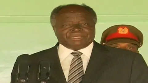 March 2009: President Mwai Kibaki flanked by first Lady Lucy Kibaki address members of the press following widespread reports of his alleged second family with business lady Mary Wambui. Wambui succeeded Kibaki as Othaya MP in 2013. #fyp #History #kibaki #kenyantiktok #surualifupi 