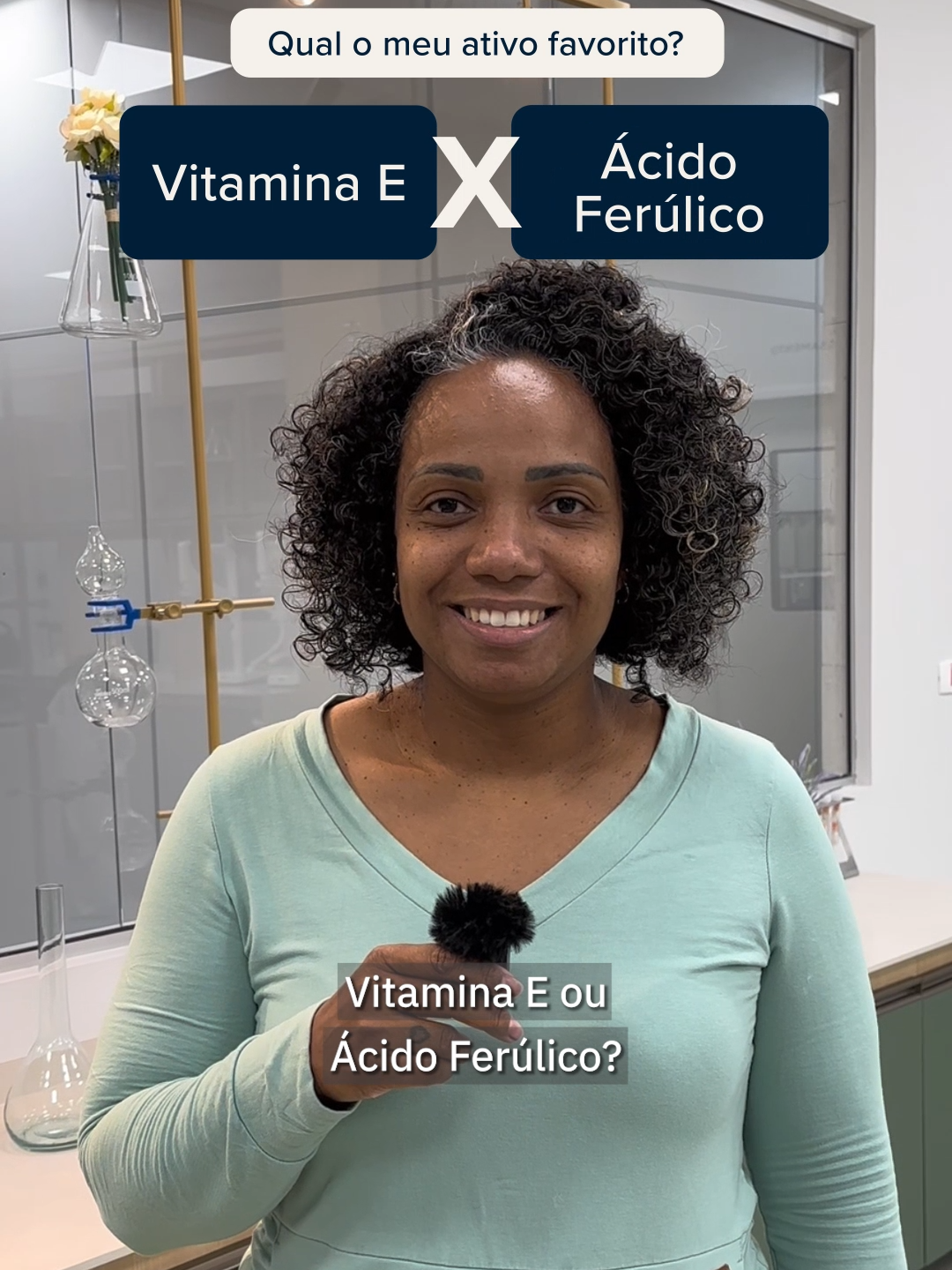 E você, prefere qual dos ativos dos produtos das marcas do #GrupoBoticario?✨ #beleza  #PraGeralVer: Uma mulher negra responde perguntas, falando qual ativo farmacêutico de produtos de beleza mais combina com ela. Ela tem cabelos pretos com algumas mechas brancas, cacheados e curtos. Veste uma blusa de mangas longas azul-claro e segura um microfone em sua mão. Na parte superior da tela, em fundo branco e letras azul-escuras, o texto: 