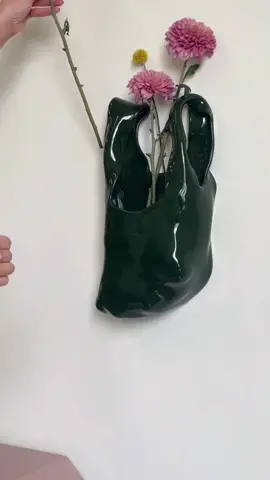 Wall hanging grocery bag vase in limited edition colorway: Chrome Green 💚💚 perfect green to pair with bright summer blooms.  I originally made this for my mom bc her favorite color is green, but loved it so much I wanna keep it around for a bit! You can pre order at emholmieceramics.com  #bagvase #wallhangingvase #ceramicart #interiorsesign #handmade 