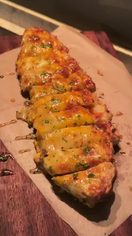 future wife: nak cheesy garlic bread me: okay jomz #fypシ #hothoney #garlicbread #cheesygarlicbread #tiktoksg #MYFoodie #foryoupage  go through the recipe with me~ (Hot Honey Cheesy Garlic Bread 🍯🧄🥖) 📝Ingredients: [To roast] 2 heads of garlic 3 shallots/ small onion extra light olive oil sprinkle of salt & black pepper 125g unsalted butter sprinkle of salt & black pepper 1 thick french loaf 1 block of mozzarella cheese 1/2 block of sharp cheddar [Hot Honey] 4 tbs honey 1 tsp chilli flakes 1 tsp sriracha Parsley Process 🔪🥘 (1) Preheat oven to 180C. (2) Cut the tops of the garlic heads and shallots. Drizzle generously with olive oil and sprinkle with salt and black pepper. Wrap them up with a foil and roast for 1 hour. Set aside to cool. (3) Grate Cheese and prepare hot honey: in a saucepan, combine honey, chili flakes and sriracha and mix on low heat for a few mins. Pour into a bowl and let it cool.  (4) In a bowl, add squeezed garlic and shallots, butter, salt and black pepper. Mash until it becomes a spreadable paste.  (5) Slice bread into half and spread the garlic butter on both sides and cheese. (6) Set the oven to grill mode and bake it further for 15-20 mins or until the cheese is melted. (7) Garnish the bread with parsley and drizzle with hot honey!