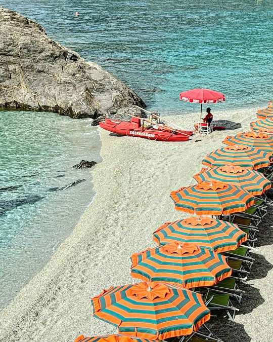 Monterosso al Mare, Cinque Terre✨💦☀️ Beach lovers should definitely stay in Monterosso which is the largest of the five coastal villages known as Cinque Terre. The town has several beaches both private and public. This private beach is called Bagni Eden which is recognized by its orange and blue striped umbrellas and it is near the train station.  #roomwithaview #shotoniphone #iamatraveler #beautifuldestinations #voyaged #italy #cinqueterre #monterosso #tlpicks #europe 