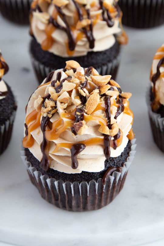 I love turning desserts and treats into cupcakes, and this is my take on a Snickers candy bar, cupcakeified! Recipe for these candy bar cupcakes on cakemehometonight.com! #candybar #cupcakes #cupcake #snickers 