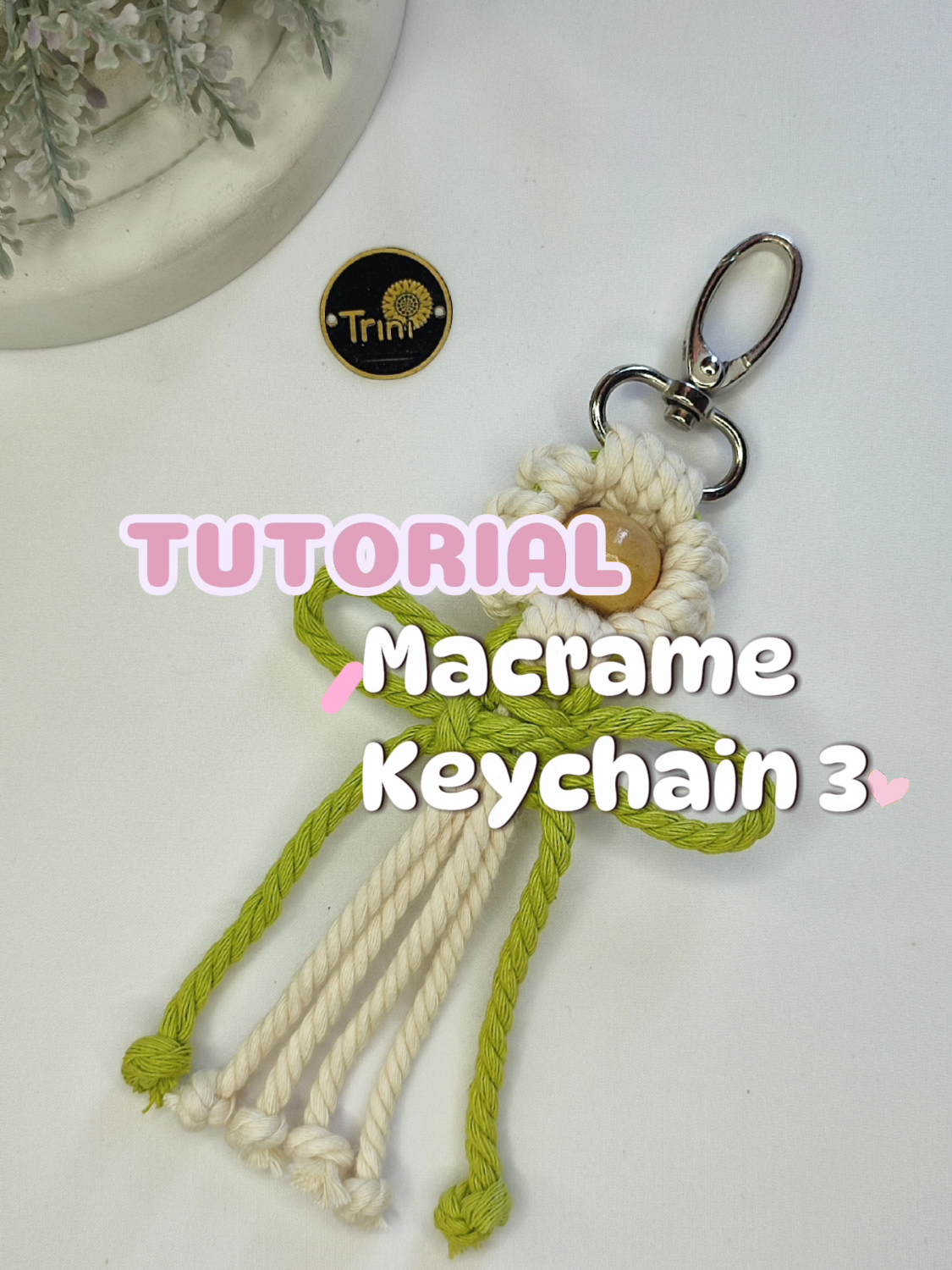 Macrame flower keychain with beads. Materials : 1. Pengait Tas/Lobster Claw Clasp Keychain 2 cm 2. Tali katun/Cotton cord 4 mm natural = 2 x 100 cm 3. Tali katun/Cotton cord 4 mm green = 1 x 70 cm 4. Manik kayu/Wooden beads 1,5 cm #macrame #diymacrame #macrametutorial #macramekeychain #keychain #keyring #macrameideas #macramecottoncords #craftontiktok #learnontiktok #craft