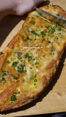 cheesy garlic bread 🧀🧄 so crunchy, cheesy, garlicky 😝 recipe:  * italian baguette  * 1 stick/ 113 g butter * 2 bulbs garlic  * 2-3 shallots * 1/4 cup parmesan  * 2 tbsp parsley  * salt + pepper  * 8 oz block mozzarella (shredded) * olive oil  cut off tops of shallots and garlic and drizzle with olive oil and wrap in foil. bake in oven at 350 F for 1 hour  once cool, squeeze roasted garlic and shallots into a bowl with your butter. (reserve the garlic oil that is left in the foil) add in your parmesan cheese and parsley and season with some salt and pepper. cut your italian loaf in half and spread your garlic butter mixture on both halves of bread. top with shredded mozzarella cheese and bake in oven preheated at 350 F for 15-20 min or until cheese is melted and golden brown. top with parsley and drizzle some of your reserved garlic oil on top 🔗full recipe also on my website linked in bio! #garlicbread #cheesy #garlic #bread #Recipe 