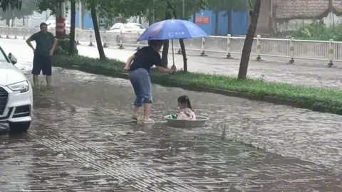 How happy she is! That will surely be her precious childhood memory. So, what's yours? #childhood #happylife #happy #rainydays #China #SummerChina #summerinChina #sweetmemory Credit to 777574997 on Douyin.