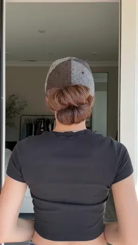 The Double Stacked Hat Bun 💁‍♀️ Pull your hair through the opening of a baseball cap and secure it with a soft, stretchy hair tie. On the final wrap, open the hair tie wide and insert your hand through the opening. Drive your hand down under the ponytail through the hair tie so that it’s now wrapped around your wrist. Pull your hand and hair tie back to create space for your hand to go up through the opening in between your thumb and the hair tie. Once your hand is through the opening, wrap your hand around the base of the ponytail. Using your other hand, pull the section of hair tie currently resting on your thumb up and over the base of the hair tie. Gently pull the bun to expand for a cute, double-stacked messy bun! #hair #hairtutorial #updo #hairstyles 