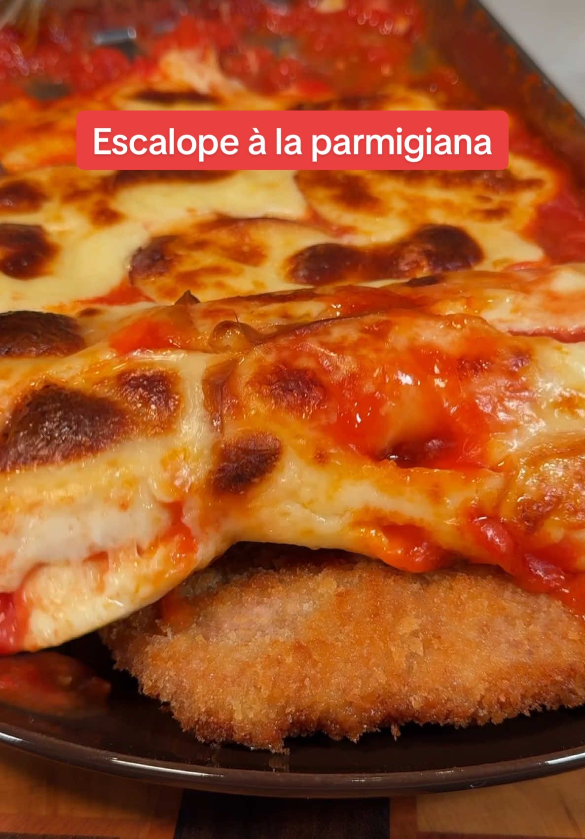 Babe me fait une Escalope de veau à la Parmigiana 🥩🧀🍅 Ingrédients : - 1 escalope de veau - 2 œufs - Chapelure panko - Farine - 1 boîte de tomates pelées - 2 gousses d'ail - 2 blancs de cébettes - Huile d'olive - 1 branche de basilic - Mozzarella de cuisine - Scamorza - Sel & poivre Recette : - Prépare la sauce tomate en faisant revenir l'ail haché et les blancs de cébettes dans un filet d'huile d'olive. - Ajoute les tomates pelées en les écrasant pour obtenir une sauce. - Ajoute quelques feuilles de basilic et laisse mijoter à feu doux pendant 45 minutes. - Aplatis l'escalope de veau entre deux feuilles de papier sulfurisé à l'aide d'un rouleau à pâtisserie. - Pane l'escalope en la passant successivement dans la farine, l'œuf battu, puis la chapelure panko. - Fais-la revenir dans une poêle avec un peu d'huile 2 à 3 minutes de chaque côté, puis laisse-la reposer. - Sur une plaque allant au four, étale la sauce tomate, puis ajoute des morceaux de mozzarella et de scamorza par-dessus. - Fais fondre le tout sous un four très chaud en mode grill jusqu'à ce que le fromage soit bien doré. - Verse la sauce tomate et le fromage fondu sur l'escalope. - Déguste tout de suite c’est un vrai banger !! #veal #parmigiana #milanese #asmrfood #food #FoodTok #homecooking 