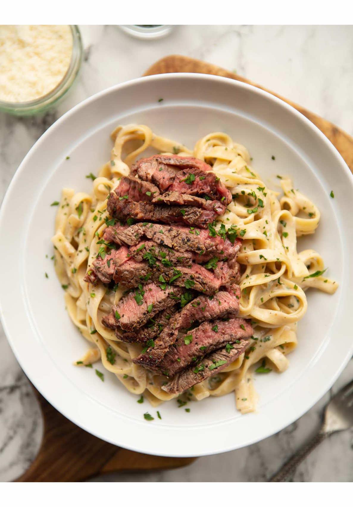 I don’t eat steak pasta enough - literally 2 of my favourite things combined! Add some Boursin in the mix and it’s game over. Hope you love it 😄 Chris xx STEAK PASTA | Serves 2 INGREDIENTS 1x 285g/10z Ribeye Steak or steak of choice, at room temp* 1 tbsp Veg Oil 1 heaped tbsp Unsalted Butter 200g / 7oz Tagliatelle, or other long-cut pasta (dry weight) 2 small Shallots, finely diced 120ml / 1/2 cup zero salt Chicken Stock 1x 150g/5.3oz block of Garlic & Herb Boursin Cheese, leave at room temp 20g / 1/4 cup freshly grated Parmesan, plus more to serve if desired 1 tbsp finely diced Fresh Parsley, plus more to serve if desired Salt & Black Pepper, as needed METHOD 1️⃣Pat the steak dry then generously season both sides with salt and pepper. Place a large cast-iron or heavy-based pan over high heat. Once the pan is piping hot (you may see wisps of smoke) add the oil and leave for 5-10 seconds. Add the steak and cook for around 2 minutes and 30 seconds, then flip and cook for another 2 minutes and 30 seconds, basting in butter with a minute left. Remove the steak and place on a plate to one side then lower the temp to medium. 2️⃣At this point add the pasta to salted boiling water and cook until al dente. Don't drain. 3️⃣Add the shallots to the pan and fry until soft & golden (careful they don't burn, the pan may still be hotter than medium). Pour in the stock then stir in the Boursin until melted. Stir in the parmesan and parsley, then stir in the resting juices from the steak. Bring to a gentle simmer and turn the heat to low. 4️⃣Use tongs to transfer the cooked pasta straight from the pot into the pan, embracing any excess water that comes with it. Toss in the sauce until it thickens and clings to the pasta. If it dries up you can toss in more pasta water as needed. Adjust seasoning if desired. 5️⃣Very thinly slice the steak with your knife at an angle and against the natural grain of the meat. Top the pasta with the steak, finish with parmesan and parsley if desired then serve and enjoy! *My steak was around 2.5cm thick and found 2 min 30 secs each side ended with it being medium-rare. Just use your best judgment to cook the steak to your liking based on its weight and thickness.