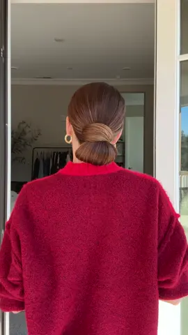 Chic low buns forever. Gather your hair into a low ponytail. Take a piece of the elastic and pull it down to create a mini loop. Push the remaining tail up and around the top of the elastic. Stuff the ends into the bottom of the elastic to secure. She’s so cute and chic! #hair #hairtok #hairtutorial 