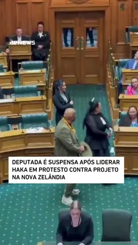 O haka, uma dança cerimonial tradicional Maori, interrompeu o parlamento da Nova Zelândia na última quarta-feira (14), durante a leitura de um projeto de lei sobre a interpretação do Tratado de Waitangi. O protesto foi liderado pela deputada Hana-Rawhiti Maipi-Clarke, do Partido Maori, que rasgou uma cópia do projeto e foi acompanhada por membros da oposição e do público. Combinando canto, gestos e movimentos intensos, o haka é usado na cultura Maori para demonstrar emoções, marcar respeito ou expressar oposição, como neste caso. O projeto de lei, criticado por questionar princípios do tratado de 1840 entre o povo Maori e a Coroa Britânica, passou em primeira leitura, e Maipi-Clarke foi suspensa. Enquanto isso, milhares continuam uma marcha de nove dias em Wellington contra a proposta. 📹 Reprodução: New Zealand Parliament/Te Pati Maori via Storyful 📺 Confira na JP News e Panflix #Haka #protesto #Parlamento #Maori #Waitangi #NovaZelândia