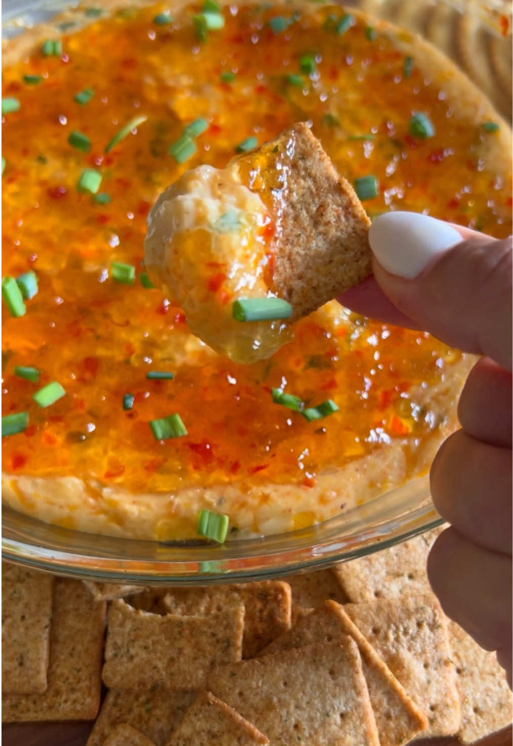 Pepper Jelly Cheese Dip! 🌶️  Ingredients: 	•	1 block (8 oz) cream cheese, room temperature 	•	4 oz shredded sharp cheddar cheese 	•	4 oz shredded pepper jack cheese 	•	1/4 cup chopped green onions 	•	1 tsp Britscookin Cajun seasoning (or your favorite seasoning) 	•	10oz red pepper jelly (divided) Instructions: 	1.	Preheat your oven to 350°F. 	2.	In a mixing bowl, combine cream cheese, sharp cheddar, pepper jack, green onions, Cajun seasoning, and 2 tbsp red pepper jelly. 	3.	Use a hand mixer to blend everything until smooth and well combined. 	4.	Transfer the mixture to a pie dish and spread it evenly. 5.	Bake for 10 minutes, just until the dip is warm and soft. 	6.	Remove from the oven and top with additional pepper jelly and chopped green onions. 	7.	Serve warm with tomato basil Wheat Thins, Ritz crackers, or your favorite dippers.