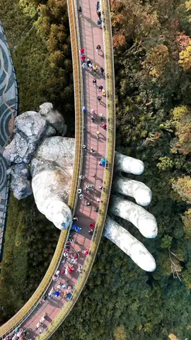 📍Złoty Most (Golden Bridge) to jedna z najbardziej spektakularnych atrakcji turystycznych Wietnamu, znajdująca się w regionie Ba Na Hills niedaleko miasta Da Nang. Most został otwarty w 2018 roku i szybko stał się ikoną architektury oraz popularnym miejscem wśród turystów z całego świata. Charakterystycznym elementem mostu są dwie ogromne, kamienne dłonie, które wydają się “podtrzymywać” złocistą kładkę unoszącą się na wysokości około 1400 metrów nad poziomem morza. Konstrukcja o długości 150 metrów oferuje zapierające dech w piersiach widoki na otaczające góry i lasy. Most został zaprojektowany tak, aby wyglądał, jakby był częścią krajobrazu, a dłonie symbolizują pomoc bogów w “podtrzymywaniu nieba”. Złoty Most jest nie tylko atrakcją turystyczną, ale również miejscem, które w doskonały sposób łączy nowoczesną architekturę z naturą. . . . . . #vietnam #việtnam #vietnam🇻🇳 #banahills #banahills🏰 #goldenbridge #goldenbridgevietnam #travelphotography #photooftheday #dronephotography #droneoftheday #earthcapture #sienawards #natgeoyourshot #natgeotravelphoto #nationalgeographic #captureeverything #djiglobal  