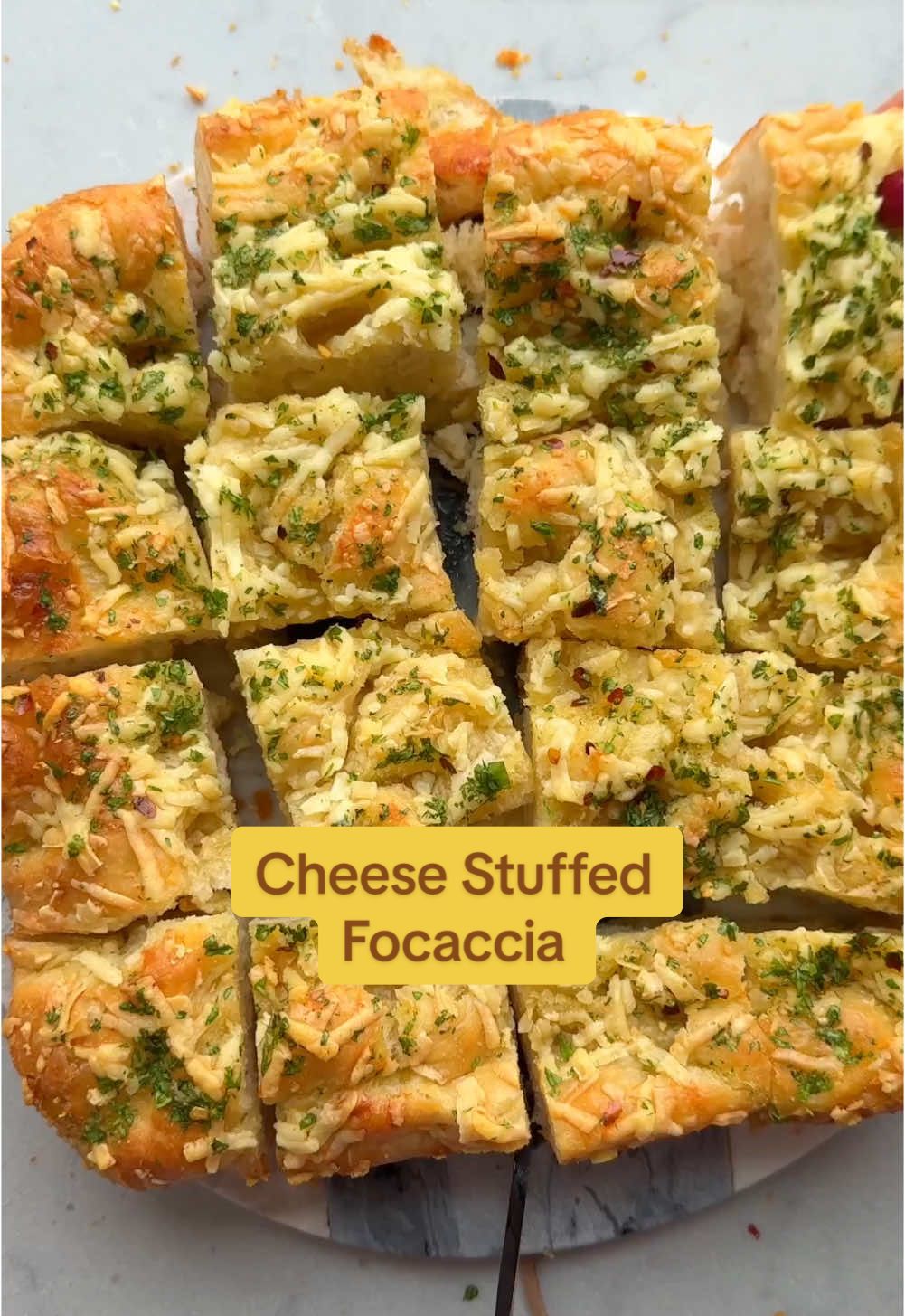 If you want an appetizer to impress, try this cheese stuffed focaccia filled with Cabot Extra Sharp Cheddar Cheese #cabotpartner. It’s naturally aged, so it’s naturally lactose free, but full of so much flavor that I nut only stuff the focaccia with it but also sprinkle it all over the top. It transforms my focaccia recipe for the holidays in something even more delicious and decadent! #sogood! #cabotcreamery #stuffedfocaccia #focacciarecipe INGREDIENTS 3½ cups all-purpose flour 1½ cups warm water 4 tablespoons olive oil, divided 1 tablespoon instant yeast 1 teaspoon salt 1 (8-ounce) block Cabot Extra Sharp Cheddar Cheese INSTRUCTIONS 1. In a large bowl, combine the flour, water, 3 tablespoons of the oil, yeast and salt. Using a rubber spatula, stir all of the ingredients together until combined, scraping down the sides of the bowl as needed. 2. Using your hands, gently shape and knead the dough together until it forms a neat ball. (You don’t need to really knead, you’re just bringing the dough together.) Cover the bowl with a clean, slightly damp kitchen towel. Set the bowl aside at room temperature until the dough has risen to double its volume, at least 1 hour and up to 12 hours. 3. Coat a 9 × 9-inch baking dish with 1 tablespoon of the oil. Transfer the dough to the prepared pan and, using your fingers, spread it over the surface of the pan until it reaches each edge. Cover the dough once again and rest at room temperature for 30 minutes longer. 4. Meanwhile, preheat the oven to 400°F. 5. Sprinkle half the shredded cheese on top of the dough and folder over in half. Using your fingers, gently press dimples all over the surface of the dough and sprinkle the remaining half of cheese on top of the dough.  6. Bake the focaccia until it’s golden brown and fragrant, 30 to 35 minutes. Remove the focaccia from the oven and allow it to cool in the pan for 10 minutes. Slice into 12 squares and serve with the labneh (if using).