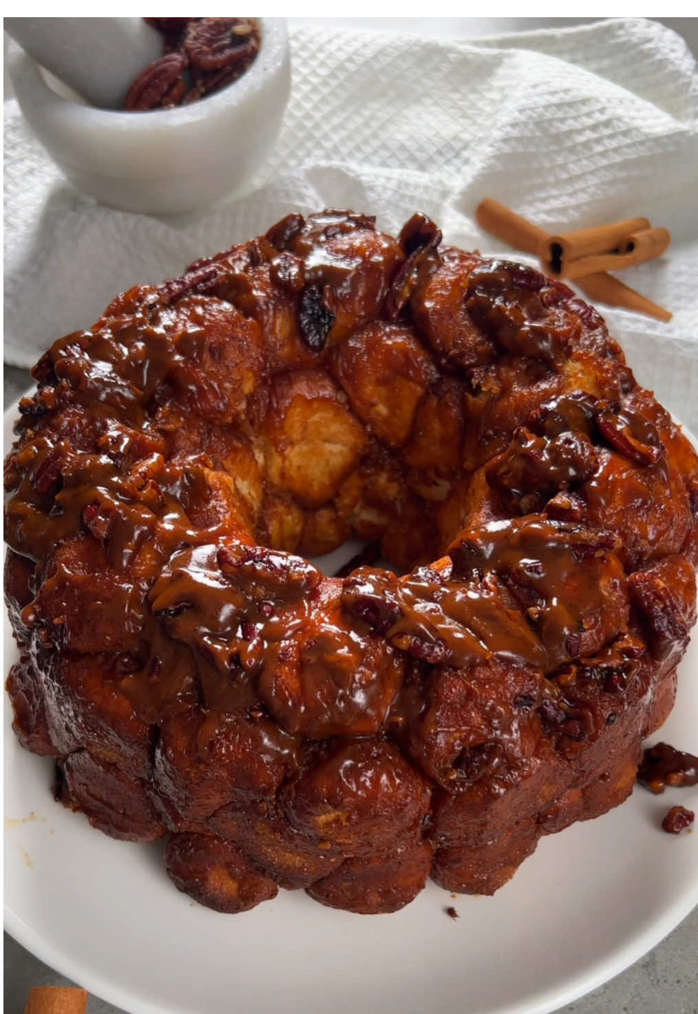 الذ خلية نحل بالقرفة والكراميل 🍯 Monkey Bread  ‏@passion.kitchen1 المقادير والطريقة: للعجينة: ٢ و ٣/٤ كوب طحين متعدد الإستخدامات ١ و ١/٢ كوب حليب دافي ٢ بيض ٢ م ص خميرة ٤ م ك سكر ٢ م ص ملح ٨٠ جم زبدة مذوبة وباردة لخليط السكر: ٣/٤ كوب سكر ٣/٤ ملعقة كبيرة قرفة للسولتد كاراميل: ١ كوب + ٢ م ك سكر ١/٢ كوب كريمه خفق ٧٠ جم زبدة ١ ملعقة صغيرة ملح بحري (ممكن اقل او اكثر ملح حسب الرغبة) مقادير إضافية: بيكان جبنة كيري الطريقة: نعجن جميع المقادير ماعدا الزبدة حتى تكون عندنا عجينة متماسكة  نضيف الزبدة تدريجياً ونعجن حتى تكون عندنا عجينة ناعمة  ولاززززم نعجن لين تكون عندنا عجينة ناعمه وماتلصق باليد لو عجانتكم ماتحمل عجن فتره طويله ممكن تريحونها اقل من عشر دقايق وترجعون تعجنون المهم لازم تكون عندنا عجينة متماسكة وناعمه وماتضيفون ابد طحين .. نخليها تخمر حتى يتضاعف حجمها بهالاثناء نجهز الكراميل وخليط السكر لخليط السكر نخلط السكر والقرفه زين .. للكراميل: نسخن الكريمه ونخليها على جنب.. نحط السكر على النار لين يصير لونة ذهبي نخلي النار على اهدأ شي ونضيف الزبدة على دفعتين ونخلط بسرعة لين تذوب وتمتزج تماماً مع السكر.. نشيله من على النار ونضيف الكريم تدريجياً وننتبه لانه بيطلع بخار قوي هنا.. بعد مايختلط نضيف الملح ونحرك..  نصفيه ونخليه على جنب.. اذا خمرت العجينة نقطعها لكور متساوية ونحشيها جبن كيري.. نرش القالب بالبخاخ المانع للإلتصاق او ندهنه بزيت ونوزع نص كمية الكاراميل والبيكان ( كمية البيكان حسب الرغبة) ولو الكاراميل برد نسخنة شوي.. نقلبها بخليط السكر والقرفه ونصفها بالصينية.. لين نملى ٣/٤ الصينية.. نخليها تخمر مره ثانيه..  قبل نخبزها نغطيها بكمية اضافية من الكاراميل.. نخبزها على درجة ١٩٠ c او ٣٧٥ فهرنهايت  مدة حوالي ٤٥ دقيقة وممكن اقل او اكثر بشوي .. نشغل الفرن من تحت وبنص الوقت من الجهتين .. او شغلوا الفرن من الجهتين من البدايه واذا تحمرت من فوق حطوا عليها قصدير بس خلوه بدون تغطية حتى مايغمق لونها.. وبالعافية