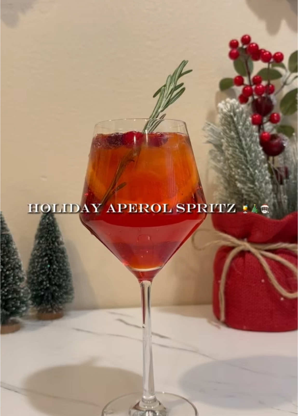 Holiday Aperol Spritz, anyone? 🍹🎄🎅🏿 Aperol Spritz is one of my favorite drinks so why not make it holiday-ish! 🥰 See below on how to make it! Ingredients: 1. Ice 2. Aperol 3. Cranberry Juice  4. Carbonated water/Soda water 5. Prosecco 6. An Orange for garnish and to enhance the citrus aromas  7. Rosemary for garnish (optional) 8. Cranberries for garnish (optional) Instructions: 1. Put ice in a wine glass 2. Pour 2oz of Aperol 3. Pour 2oz Cranberry Juice  4. Pour 1oz Carbonated Water 5. Top off with Prosecco  6. Garnish with Orange Slice, Rosemary and Cranberries. Cheers!! 🎄❤️ #aperolspritz #aperol #holiday #holidaycocktail #cocktails #prosecco #cranberries #rosemary #merrychristmas #happyholidays #itstime #christmastime #christmas #party #holidaydrinks #holidayaperolspritz #cheers