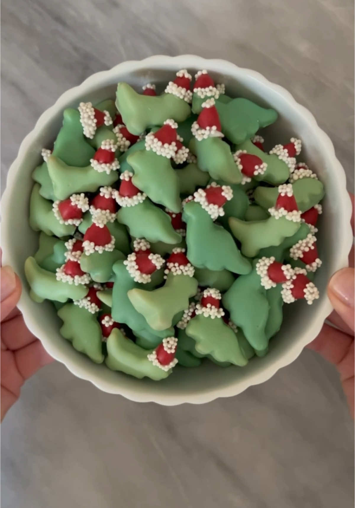 Dinosaur Cookies with Santa Hats! 🦖🦕✨ For these festive dinosaur cookies, I started with a half batch of my favorite sugar cookie recipe, shaping the dough into mini dinosaurs. To create Santa hats, I cut small circles of dough into segments to form triangles and attached one triangle to the top of each dinosaur before baking. After baking and letting the cookies cool, I dipped each cookie in candy melts. Then, I dipped the top of each dinosaur in red candy melts to form the Santa hats. For the trim, I added a line of white chocolate along the edge of the hats before dipping them into white nonpareils. Using a toothpick and melted chocolate, I applied a small chocolate dab to each hat's tip and dipped it in the white nonpareils to create the pom-pom. Cookie cutters: These mini cutters are about 1.25 inches. #baking #homemade #cookies #sugarcookies #dinosaurs #holidaybaking #food #sweets #christmasbaking #christmas