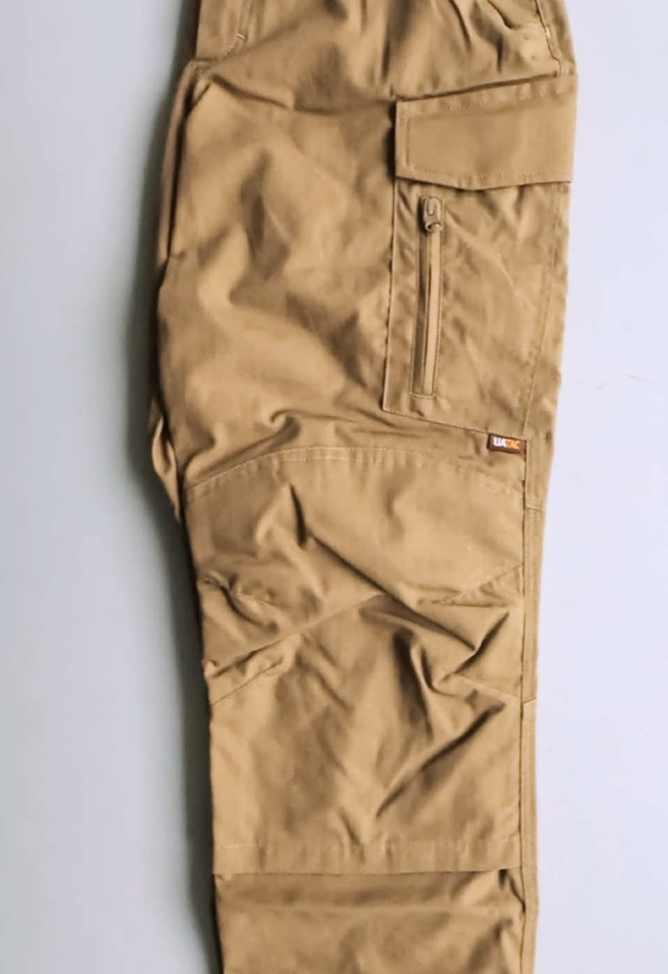 The Lite UATAC tactical pants are designed specifically for the military, have a versatile cut and are suitable for a variety of conditions of use - training, shooting range, work or walking. The fabric consists of 65% cotton and 35% polyester, which makes it pleasant to the touch and resistant to tearing and damage. Ripstop weaving will prevent the pants from tearing even under heavy loads. Large cargo pockets with Velcro.Equipped with an additional compartment for storing oversized items and a carabiner. On the side of the cargo pocket there is a zipper for convenient access while sitting. Special convenient phone pocket on the right side. Two front pockets for a knife or flashlight. Large compartment in the knee area with the possibility of installing a knee pad inside (sold separately). The belt is made elastic, with the possibility of stretching. Pants are designed to be worn with a belt up to 6 cm. Convenient Velcro fasteners on the cuffs of the pants. Fabric 65% cotton, 35% polyester. Ripstop weaving Elastic 