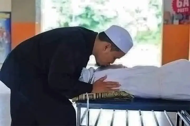 Apabila tiba giliran suami atau isteri untuk mencium jenazah, mereka akan mencium dahi pasangan masing-masing. Air mata mengalir di pipi jenazah, dan si suami atau isteri memeluk jenazah agak lama. Secara fitrah, air mata akan terkena kain kafan jenazah. Namun, seorang makcik bersuara, 