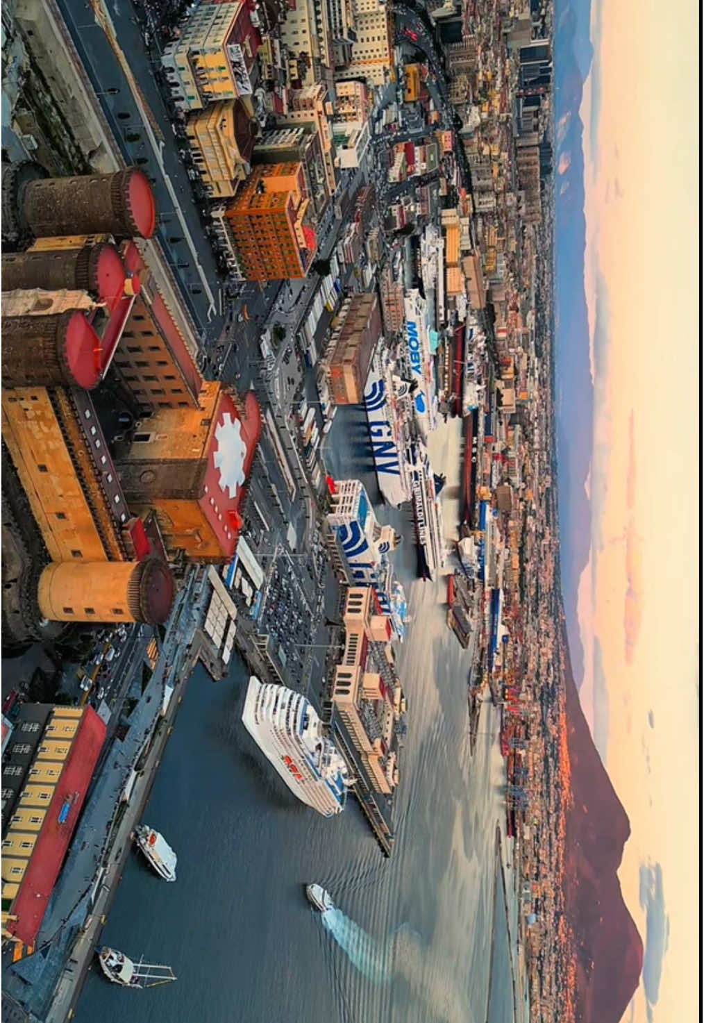 Una magnifica panorama di Napoli al tramonto dove si vede piazza del plebiscito castel dell’Ovo, la magnifica margellina immersa nel golfo di Napoli con il suo maestoso Vesuvio colorato da uno splendido tramonto #napoli #golfodinapoli #dronenapoli #napolitramonto #dovevederenapolidallalto 