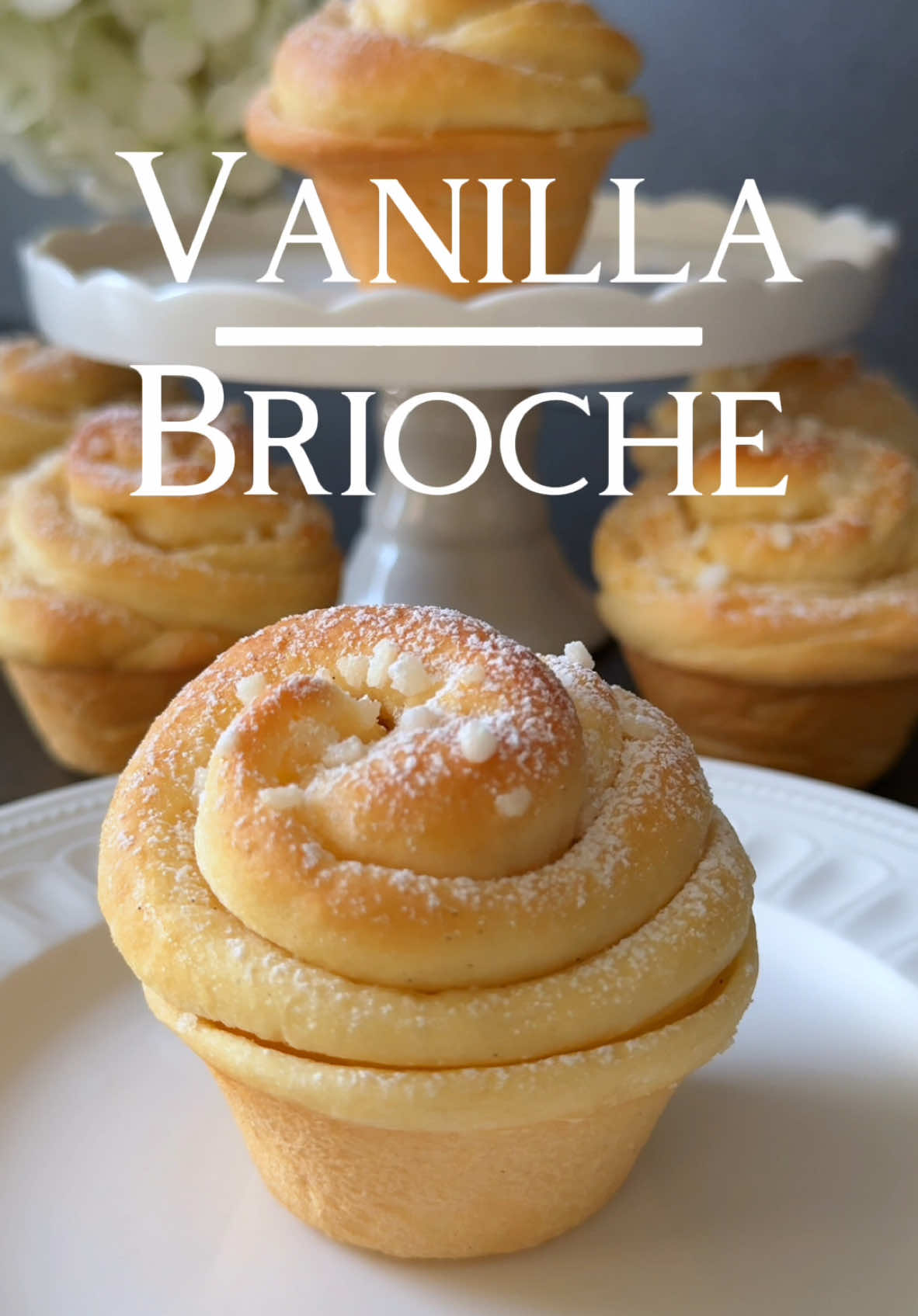 Ad | Vanilla Brioche Recipe 🤍 These Vanilla Brioche are wonderfully soft, buttery, and slightly sweet – perfect for a cozy dessert! 🥰 📝 Ingredients for the Dough: • ⁠250 g all-purpose flour (2 cups) • 30 g sugar (2 ½ tbsp) • ½ tsp salt • 125 ml lukewarm milk (½ cup) • 1 tsp dry  yeast • 1 tsp vanilla extract • 40 g soft butter (3 tbsp) • 1 egg (size M) Ingredients for the Butter Filling: • 30 g soft butter (2 tbsp) • 1 tsp vanilla extract 🤍 Instructions: 1.	Sift the flour into a bowl and make a well in the center. Dissolve the yeast with 1 tsp sugar in some lukewarm milk and pour it into the well. Lightly mix and let rest, covered, for 10 minutes until foamy. 2.	Add the remaining milk, sugar, salt, egg, soft butter, and vanilla extract. Knead the dough for 5–7 minutes until smooth and elastic. If it’s too sticky, add a little flour. 3.	Cover the dough and let it rise in a warm place for about 1 hour until doubled in size. 4.	Divide the dough into 6–7 equal pieces, shape them into balls, and roll them into rectangles. 5.	Mix the soft butter with the vanilla extract and spread it over the dough pieces. 6.	Gently stretch each piece with your hands to form a nearly square shape. Lift from the long side and fold the edges over each other in an overlapping manner. Carefully roll the dough to create a rose shape. 7.	Place the shaped brioche rolls into well-greased muffin molds, sprinkle with pearl sugar, and let them rise, covered, for about 30 minutes. 8.	Preheat the oven to 175°C (350°F) top/bottom heat. Bake the brioche rolls for 18–22 minutes until golden brown. 9.	Let them cool slightly and dust with powdered sugar. Enjoy! 🤍
