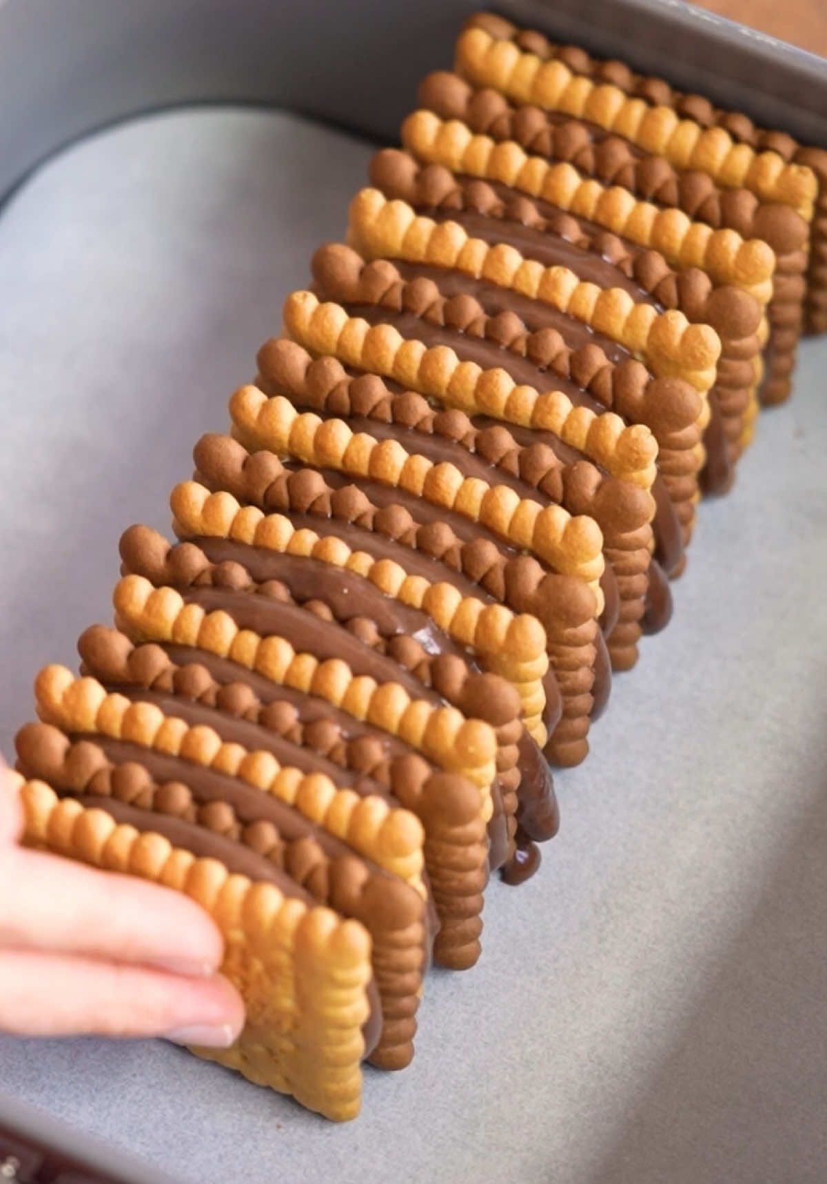 3 Malzemeli Bisküvili Pasta | 3-Ingredient Biscuit Cake 😋 Malzemeler 1 paket kakaolu puding 3,5 su bardağı süt (700 ml) 1 paket sade petibör bisküvi 1 paket kakaolu petibör bisküvi Hazırlanışı Tencereye kakaolu pudingi alalım, üzerine sütü ilave ederek karıştıralım. Ocağı açalım, koyulaşıncaya kadar karıştırarak pişirmeye başlayalım. Kaynayıp göz göz olduğunda pudingi ocaktan alalım. Petibör bisküvilerden 1 tane alarak üzerine biraz puding sürelim. Ardından bisküviyi kalıbın ortasına yerleştirelim. Bir kakaolu bir sade bisküvi olacak şekilde pudingi sürdükten sonra sırasıyla bisküvileri kalıba dizelim. Kalıbımız doluncaya kadar bisküvilerimizi art arda sıkıca dizmeye devam edelim. 2-3 yemek kaşığı kadar pudingi bir kenara ayıralım. Arta kalan pudingle bisküvili pastanın her yerini dikkatlice kaplayalım. Hazır olan pastamızı yaklaşık 2 saat kadar buzdolabına kaldırarak dinlenmeye bırakalım. İyice soğuyan ve dinlenen pastayı dikkatlice kalıptan çıkardıktan sonra açıkta kalan kenarlarını önceden ayırdığımız pudingle güzelce kaplayalım. Dilediğimiz şekilde dilimleyerek servis edelim. Afiyet olsun! . You’ll need 1 pack chocolate pudding 3 1/2 cups milk (700 ml) 1 pack plain Petit Beurre biscuits 1 pack cocoa Petit Beurre biscuits 1 cup = 200 ml Here’s how Pour the chocolate pudding mix into a pot, add milk, and stir well. Cook over medium heat, stirring continuously until thickened. Remove from heat when it begins to boil. Spread pudding on a biscuit and place it vertically in the center of a mold. Alternate plain and chocolate biscuits, spreading pudding between layers, until the mold is full. Reserve a few spoonfuls of pudding for later. Cover the assembled cake with the remaining pudding and chill for 2 hours. Once set, remove from the mold, coat exposed sides with reserved pudding, slice, and serve. Enjoy! #nefisyemektarifleri #nefisyemektariflerinden #tarif #tarifler #bugünnepişirsem #food #cooking #Recipe #recipetok #TiktokMutfağı #Nublê 