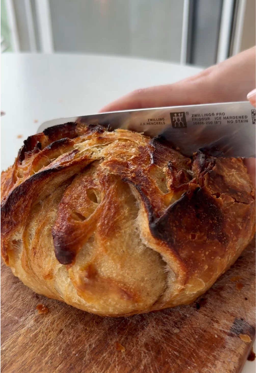 Crispy, flaky cinnamon sugar Sourdough bread✨🍞🌾 Buttery, messy and delicious!  Is it better than a cinnamon bun? Not quite. Would I make it again? Probably not😂 But it was a fun little experiment. Recipe and step-by-step instructions below if you’re up for something different.  Recipe: 400g Bread Flour  305g Water 80g sourdough starter 8g Maldon Sea Salt (or regular salt) 80g Frozen Butter 2dl Sugar 3tsp Cinnamon Instructions: 1️⃣ In the morning, feed 25g of starter with 50g flour and 50g water (I use 40g unbleached bread flour and 10g rye). Mine peaked in about 5 hours.  This makes a bit extra, so you’ll have some freshly fed starter to store in the fridge for next time.  2️⃣ Once peaked, dissolve 80g starter in 300g water. Add the flour and mix until no dry flour remains. Cover and rest for 30 minutes.  3️⃣ Add the salt and 5g water. Mix well. Place your butter in the freezer.  Over the next 2 hours, perform 4 sets of coil folds, spaced 30 minutes apart.  4️⃣ Turn your dough onto a surface sprinkled with some water (helps prevent sticking). Stretch the dough as thin as you can without tearing it. Grate most of the frozen butter evenly over the dough. Use your hands to lightly press the butter so it sticks.  5️⃣ Fold the top toward the center and the bottom up over the folded top, so you have a layered rectangle. Add the rest of the frozen butter and fold the dough up into a neat little parcel.  6️⃣ Return the dough to its container. Cover and let it rise until it has grown ~75-100% from its initial size. In cooler temperatures, I let the dough double in size, If it’s warmer, I refrigerate it earlier to slow fermentation. Temperature is really important for this loaf, as too high temperatures can make the butter melt. For references, my dough doubled in size in about 8 hours at ~22°C. 7️⃣ At the end of bulk fermentation, turn the dough onto a lightly floured surface and shape into a ball. Cover and let it bench rest for 15-30 minutes. Prep your cinnamon sugar mix.  8️⃣ Flip the dough so the smooth side is facing down. Gently stretch the dough into a circle. Sprinkle most of the cinnamon sugar mix and lightly press it into the dough. Fold the left side over center, then the right side over the left, overlapping each other. Add the rest of the cinnamon sugar mix. Roll it up and seal the ends. Place the dough seam-side up in its banneton.  Cover and transfer to the fridge for 12 hours cold proof.  9️⃣ In the morning, preheat your dutch oven at 250°C for 45-60 minutes. I bake my bread for 20 min at 240°C with the lid on, followed by 20 min at 220°C with the lid off. Enjoy! Please note Rather than relying on a time period for your bulk rise, you should rely on visual cues. Sourdough is all about experimenting and adapting based on your experiences, and it may take some trial and error to know what works best for you.  #sourdough #surdeig #sourdoughbread #cinnamonrolls 