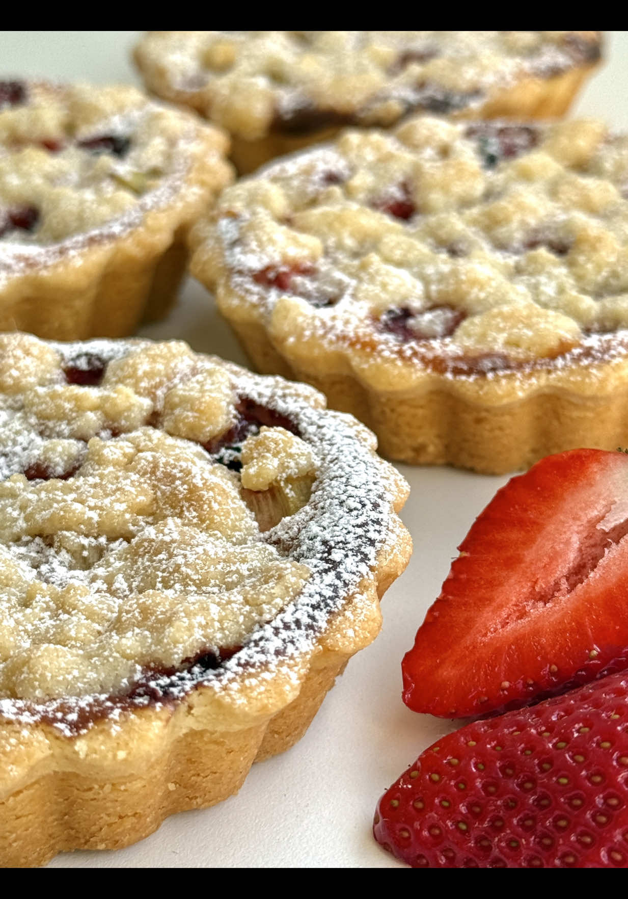 Ad | Rhubarb Strawberry Tartelettes Recipe 😍🤍🍓 A crispy crust, fruity filling and buttery crumbles – these little tartelettes are the perfect way to enjoy spring in every bite! 🥰 📝 Ingredients for 5 tartelettes (10 cm / 4 inches in diameter) For the shortcrust pastry: •	150 g all-purpose flour (1 ¼ cups) •	50 g sugar (¼ cup) •	1 pinch of salt •	90 g cold butter, cubed (6 ½ tbsp) •	1 egg yolk •	1–2 tsp ice-cold water (as needed) For the cheesecake filling: •	250 g low-fat quark or unsalted cream cheese, at room temperature (1 cup) •	50 g sugar (¼ cup) •	1 egg (medium) •	1 tsp vanilla extract •	1 tsp cornstarch For the fruit layer: •	80 g rhubarb, peeled and chopped (½ cup) •	80 g strawberries, washed and chopped (½ cup) For the crumble topping: •	50 g flour (⅓ cup) •	30 g sugar (2 ½ tbsp) •	40 g cold butter, in small cubes (3 tbsp) 🤍 Instructions 1.	Combine flour, sugar, salt and butter using your hands or a dough hook until crumbly. Add the egg yolk and 1–2 tsp of cold water and knead briefly until a smooth dough forms. Wrap in cling film and chill for 30 minutes. 	 2.	Roll out the dough and press it into 5 non-stick tartelette pans (ideally with a removable base). Prick the bottoms with a fork. Add a small layer of chopped rhubarb first, then spoon over the cheesecake filling. Top with the strawberries and remaining rhubarb (you can gently mix them together if you like). 	 3.	Stir together the quark or cream cheese, sugar, egg, vanilla extract and cornstarch until smooth. 	 4.	Quickld rub flour, sugar and cold butter together with your fingertips or a fork until you get coarse crumbs. Do not overmix – the butter should stay cold to create buttery crumbles. Chill until ready to use. 	 5. Sprinkle the prepared tartelettes generously with the crumble topping. Bake in a preheated oven at 175 °C (350 °F) top/bottom heat for about 30 minutes, until golden and set. 	 6.	Let the tartelettes cool completely before carefully removing them from the tins. Dust with powdered sugar if desired.  Enjoy warm or chilled! 🥰