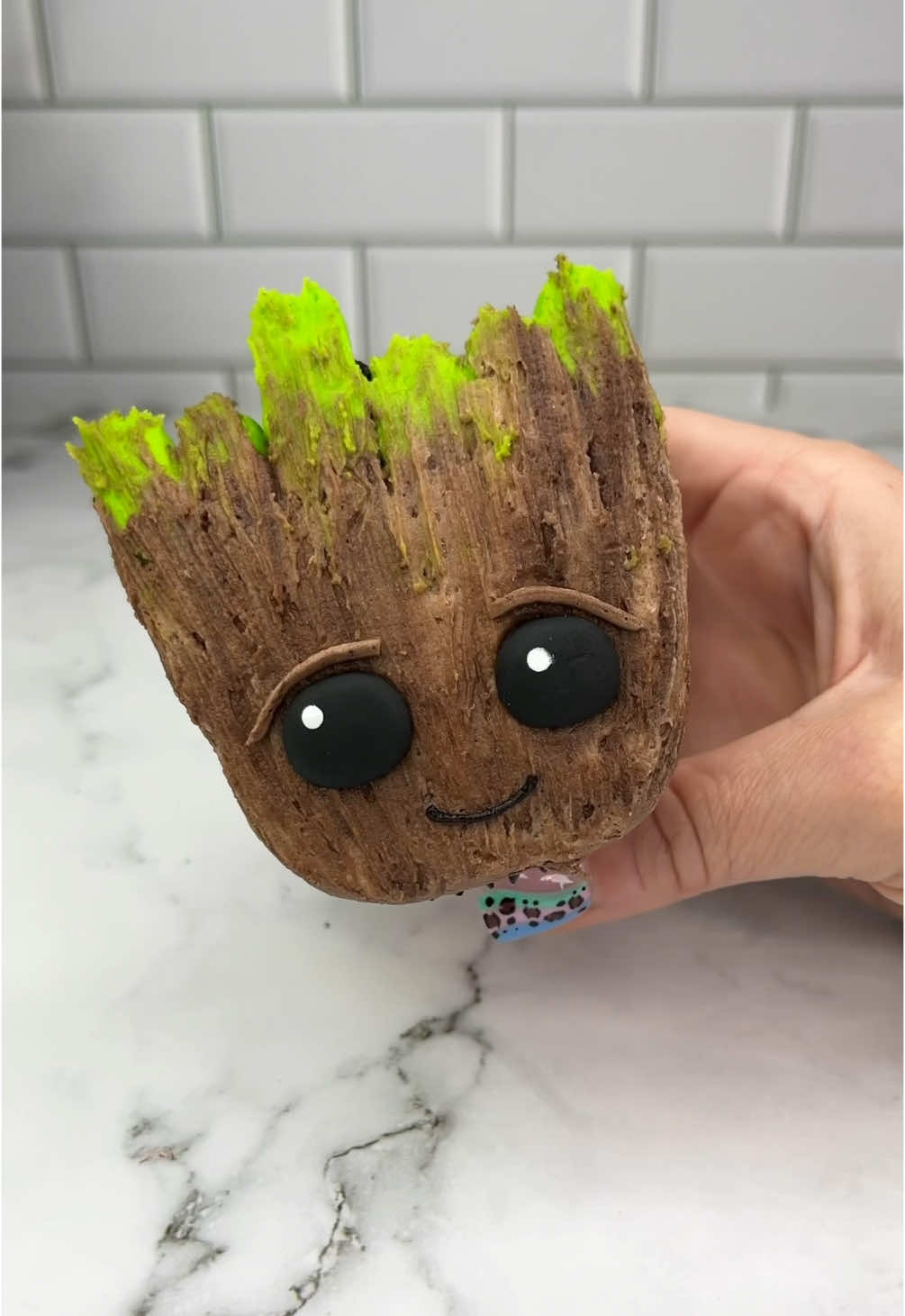 I am Groot 🤎💚 Turning a cupcake into baby Groot 🪴💚 I used buttercream to attach Oreo halves to the top of the cupcake and then popped it in the fridge to see in place. I then piped two tone chocolate buttercream, followed by green buttercream in the shape of his face. I used a silicone brush to add texture. The eyes are made from fondant. 🤎💚 #cupcake #cakedecorating #groot #guardiansofthegalaxy #cakedbyrach #cakeartist #cupcakesforanyoccasion 