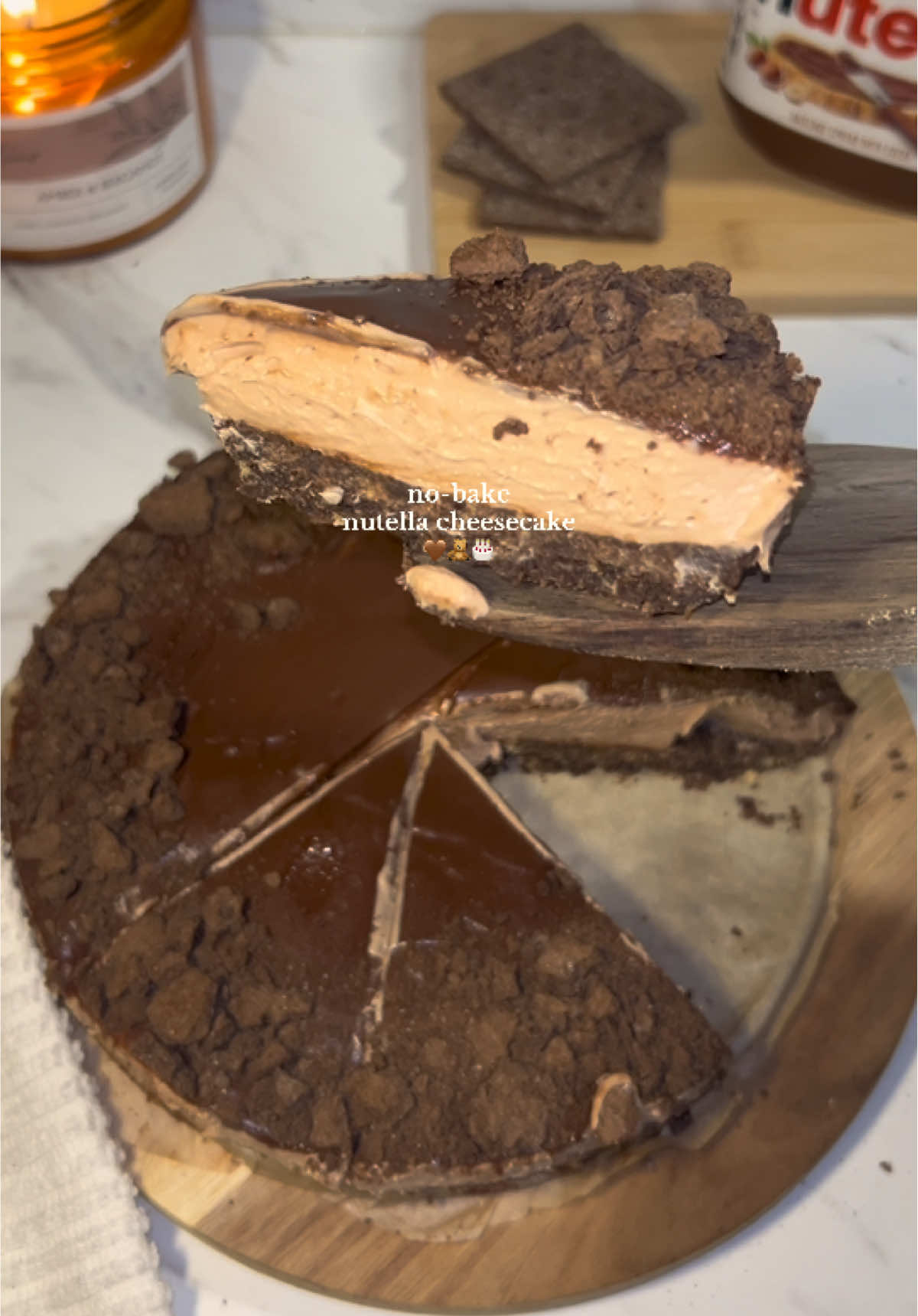 homemade nutella cheesecake 🤎   recipe:   8oz cream cheese (softened) (226g) 1/3 cup powdered sugar (40g) 1 tbsp lemon juice (15g) 1 tbsp vanilla extract (1-3g) 1/2 cup heavy cream (120g) 1 tbsp sugar (13g) 1/4 cup nutella (75g) 1 1/2 cups of chocolate graham crackers (crushed) (150g) 6 tbsp butter (85g) (melted)   -line the bottom of your pan with parchment paper then crush your graham crackers & mix with melted butter, spread onto bottom of pan and place into the fridge. in a bowl mix together cream cheese, powdered sugar, vanilla, & lemon juice until combined, then add in 1 heaping tbsp of nutella. in a seperate bowl mix your heavy cream and sugar until a stiff peak forms, then fold into your cream cheese mixture. let cool for about 2-3 hours then take it out and pour melted nutella on top. let cool for another 30 minutes. slice & enjoy! :))   #nutella #cheesecake #cake #Recipe #bakingrecipe #baking #fyp 