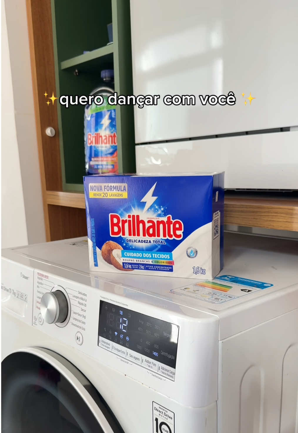 Até a nossa máquina de lavar entrou na vibe e tá dançando com o seu par perfeito. 🧺💃 #Brilhante #PraTodosverem: No vídeo, vê-se um armário planejado com uma máquina de lavar roupas. A máquina tem abertura frontal. Sobre ela, há uma caixa de sabão em pó da marca Brilhante, que balança levemente com a vibração da máquina. Em um nicho do armário, está uma embalagem de sabão líquido Brilhante. Na parte superior da tela, aparece o texto “quero dançar com você”, em letras brancas.