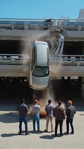 A car, after a crash, was left hanging dangerously off a parking structure. Curious onlookers, mostly guys, gathered below to take photos and watch. But suddenly, the car gave way and crashed down—landing just inches away from them. They were incredibly lucky. The car? Completely wrecked #crash #crashed #damage #ai #news #car #collapse #city #bridge #911