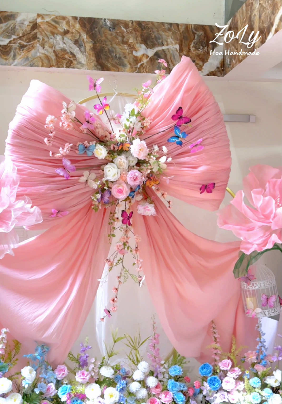  🎀 Vì một backdrop đẹp… là nền cho khoảnh khắc đời người. 💞 Một chiếc nơ khổng lồ cho backdrop cưới –  Voan tơ nhập, xếp nếp layer, nhấn giữa bằng hoa và bướm lụa bay cao cấp. Chụp hình cưới? Decor lễ thành hôn? Studio hay wedding planner đều có thể custom theo tone. #ZoLyHoaHandmade #BackdropCướiHàn #LuxuryDecor #NơCướiHandmade #VoanTơCaoCấp #WeddingStylingVN #FloralDesignStudio #decorcafe 