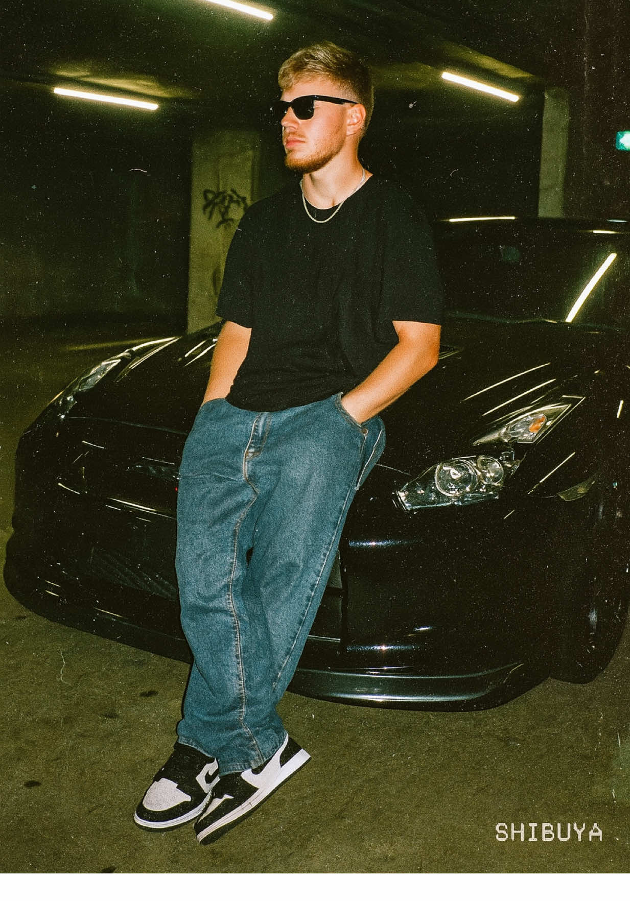 TOKYO UNDERGROUND 🇯🇵💯 From a simple selfie → to a full-blown 35mm street film shot. No retouching. No filters. Just raw style, attitude & underground energy. ⠀ The prompt 👇 Create a gritty, cinematic analog-style 35mm film photograph based on a side-profile selfie. The subject leans back confidently on the hood of a parked Nissan GT-R inside a dimly lit underground parking garage in Shibuya. Harsh fluorescent lights reflect off the polished car surface and wet concrete floor, casting moody shadows around the scene. The face must remain exactly as in the original selfie — no AI retouching, no smoothing, no changes. Preserve all natural facial features 1:1, including skin texture, hairstyle, expression, and proportions. The subject wears a black oversized T-shirt and baggy jeans, paired with black-and-white Nike Air Jordan Lows. Black sunglasses complete the laid-back but bold aesthetic. Accessories like a waist chain or subtle rings are optional. The subject faces slightly off-camera, showing side-profile calmness and quiet confidence — like a paused moment from a street racing film. Use a direct flash with expired 35mm film effect: blown-out highlights, soft glare, heavy analog grain, and slight light burns on the frame edges. Background details include concrete pillars, faint graffiti, blurred exit signs, and glowing strip lights with a greenish tint — all creating a raw, underground energy. The entire Nissan GT-R should be visible in the composition — angled slightly, headlights off, its curves catching fragments of garage light. Final look: lo-fi, cinematic, street-cool — like a behind-the-scenes still from a AndAfter  #Aledits #ChatGPTPrompt #TikTokTips #ViralHack #ProfessionalPhoto #BeforeAndAfter