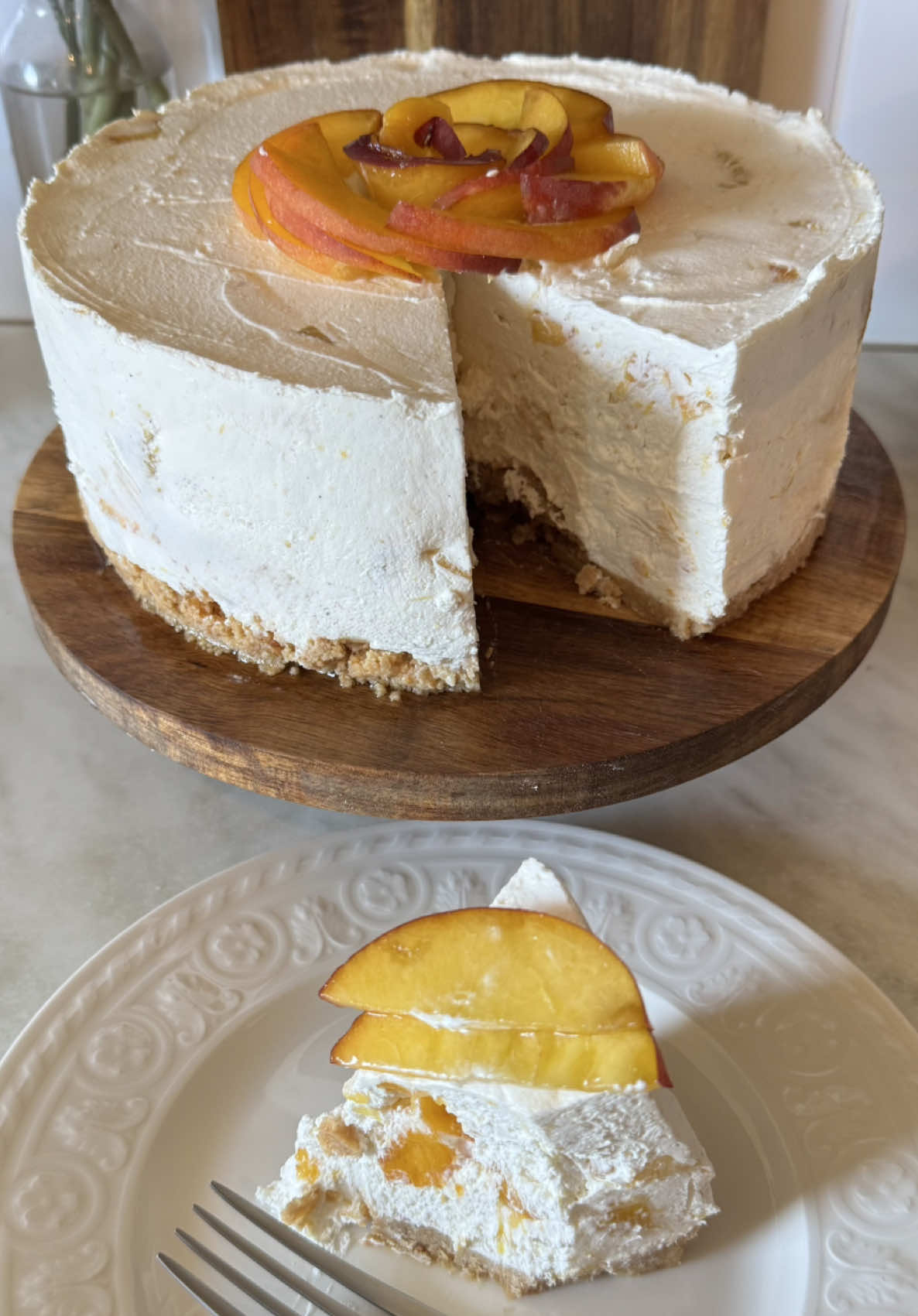 BRESKVA CHEESECAKE 🍑 Podloga: 200g mljevenog keksa 100g otopljenog maslaca 5 žlica mlijeka Sve promiješati i utisnuti u kalup 24 ili 26cm.  Krema: 5 zrelih breskvi (mogu i nektarine) 180g smeđeg šećera 1 vanili šećer ili 1 žličica ekstrakta/paste od vanilije 400ml vrhnja za šlag 400g krem sira sok od 1 limete Breskve oguliti, lako se gule kada su zrele, te ih narezati na ploškice ili na kockice. Pola staviti u lonac sa šećerom, sokom limete i vanilijom te na laganoj vatri karamelizirati 10-15 minuta. Ostaviti sa strane da se ohlade. Smiksati vrhnje za šlag, dodati mu sir te sve sjediniti. U tu smjesu dodati karamelizirane i svježe breskve, sve promiješati te rasporediti po podlozi od keksa. Ohladiti preko noći. Po želji napraviti preljev od 200g bijele čokolade i 100ml vrhnja za šlag te preliti po torti.  Ako želite, možete karamelizirati svo voće umjesto da pola ostavite svježe. Ja preferiram kombinaciju jednog i drugog. Kalup možete izvana obrubiti folijom jer svježe breskve nekad mogu pustiti malo tekućine, ali uglavnom nisu ukoliko su dovoljno zrele. #LucinaSpiza #fyp #ajmokuhat #breskva #cheesecake #recept #foryou #kuhinja #ručak #desert 