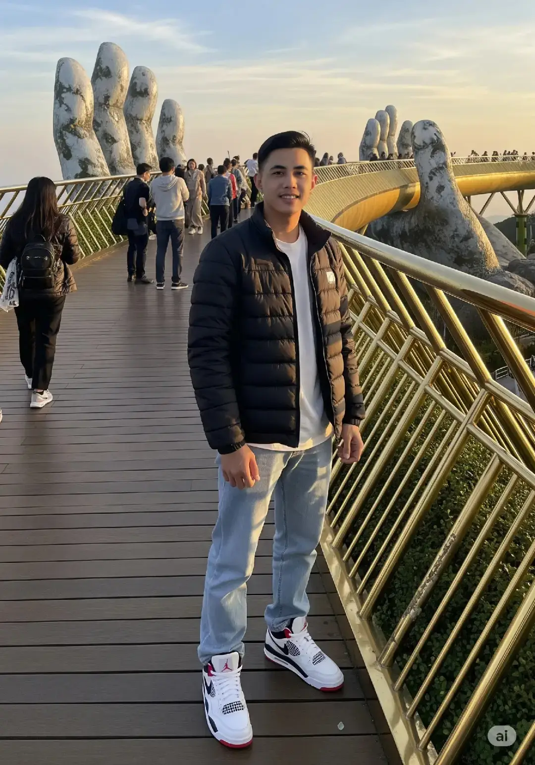 Prompt : Buat foto seorang pria muda khas Indonesia yang berdiri di atas Jembatan Emas (Golden Bridge) yang ikonik di Ba Na Hills, Da Nang, Vietnam. Berikut adalah deskripsi detail dari foto tersebut: Subjek Utama: Pria muda berdiri di tengah jembatan, menjadi fokus utama foto. Ia mengenakan jaket tebal hitam model puff dengan hoodie, kaus berwarna putih di dalamnya, serta celana jeans longgar berwarna biru muda. Sepatu yang dipakai nike warna putih merah dan hitam. Posisi tangan diletakkan menyilang di depan tubuh dengan ekspresi wajah yang sedikit tersenyum melihat kedepan camera. Latar Belakang: Lokasi berada di Golden Bridge, sebuah jembatan terkenal yang tampak seolah-olah diangkat oleh dua tangan raksasa batu. Di belakang pria, terlihat beberapa wisatawan, sebagian besar sibuk mengambil foto atau melihat pemandangan. Tangan batu besar yang menopang jembatan tampak sangat jelas dan menjadi elemen visual yang mencolok di latar belakang. Rel pembatas jembatan berwarna emas keemasan dengan struktur unik berbentuk silang diagonal. Vegetasi hijau tampak di sisi kanan bawah jembatan, menambah kesan alami dan segar. Latar langit berwarna biru lembut dengan semburat oranye kekuningan di cakrawala, mengindikasikan waktu menjelang senja atau pagi hari. Pencahayaan dan Suasana: Cahaya hangat dari matahari menyinari bagian kanan wajah dan tubuh pria, menciptakan nuansa keemasan alami yang memunculkan detail tekstur jaket dan jembatan. Aspek 3:4. #chatgpt #faceswap #f #fyppppppppppppppppppppppp #fyp #gemini #Ai 