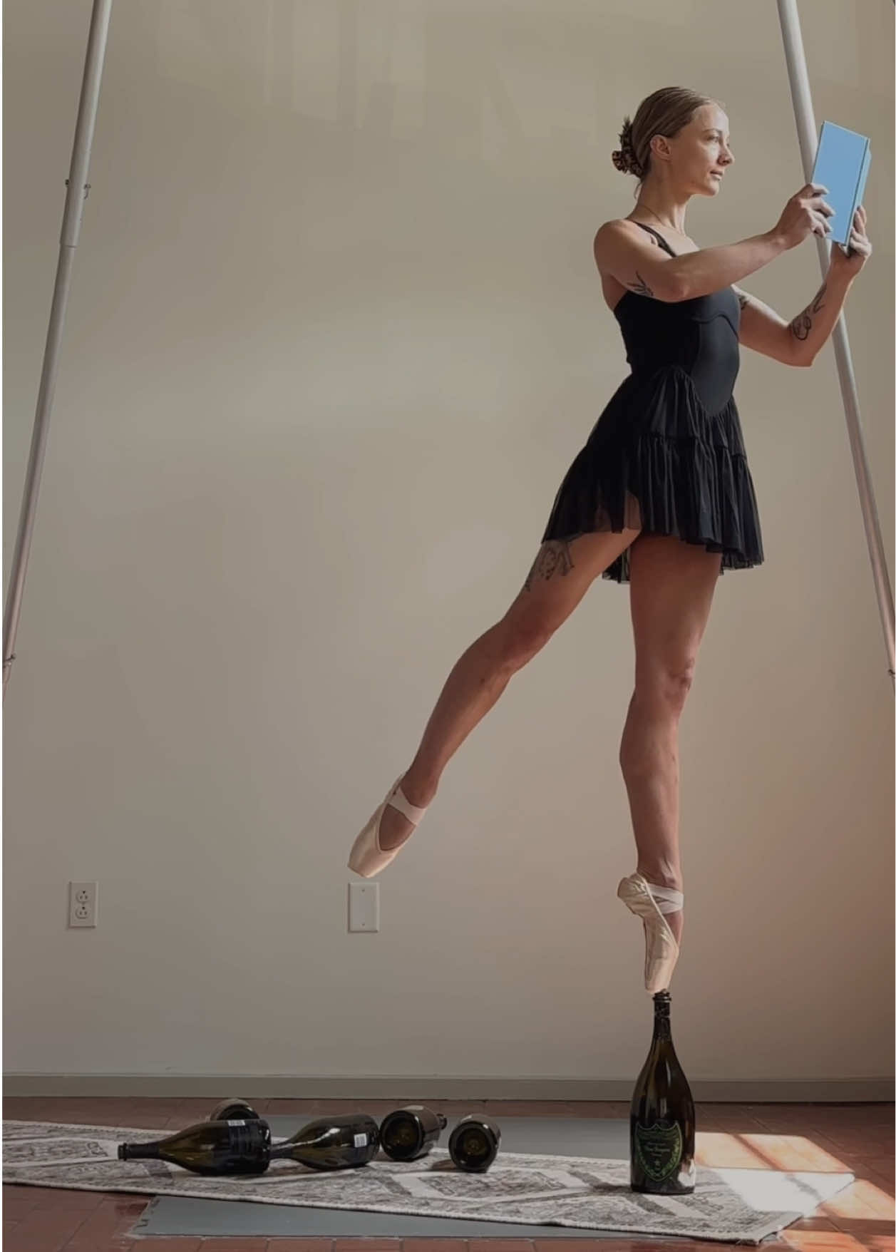 Upped my book reading and pointe bottle walking game! Smaller bottles (smaller bottles are harder to stabilize yourself on) and knocking them over 🩰✨🖤🍾🤗 spoiler alert: I’m not actually reading the book, but I feel like a pretty ballerina and I’m proud of myself 💪🏻😂 #enpointe #pointe #ballet #ballettok #ballerina #ballerinasoftiktok #dance #circus #gymnastics #enpointebottlewalking 