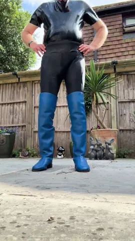 Man wearing blue thigh high boots over black leggings and a black latex vest.#thighhighboots #overthekneeboots #tallboots #leatherboots #leather #latex ##shinyleggings 
