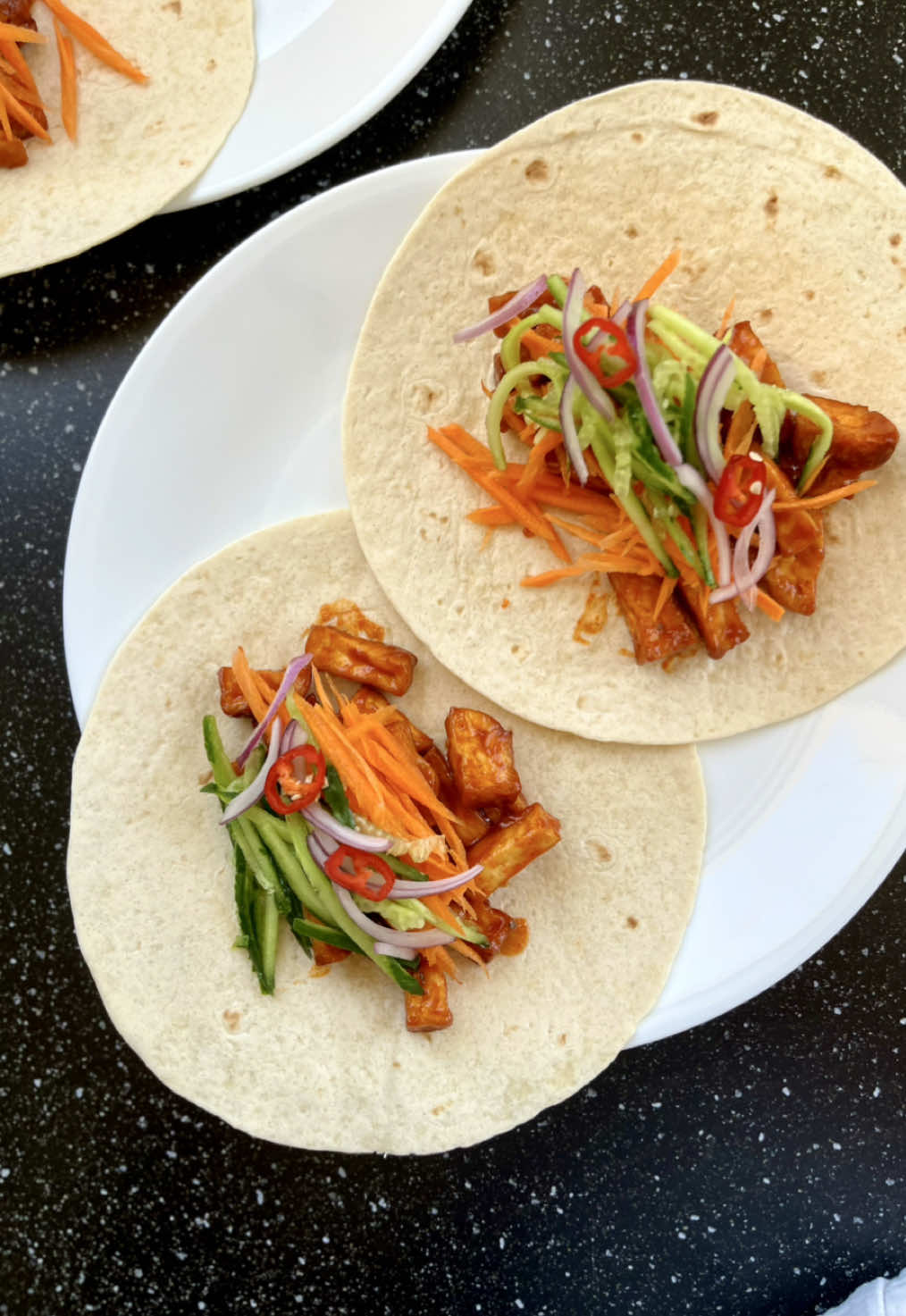 טאקו טופו בגוצ׳וג׳אנג 🌶️🌮| מתכון ✨ לקחתי 200 גרם טופו, חתכתי לקוביות, שמתי חצי כף קורנפלור וקצת שמן, ערבבתי ונתתי לו 20 דקות באייר פרייר על חום גבוה, עד שהטופו קריספי מבחוץ. (אפשר גם בתנור אם אין אייר פרייר, פשוט ייקח יותר זמן). בינתיים במחבת שמתי: 	•	חצי כף גוצ׳וג׳אנג 	•	בערך שליש כוס מים  	•	כפית סוכר 	•	חצי כפית רוטב בולדאק (או צ’ילי גרוס אם אין לכם) 	•	חצי כף סויה מערבבים ונותנים לזה לבעבע כ 5 דקות עד שהרוטב מצטמצם קצת (זה בסדר שהוא עדיין נראה נוזלי – הוא יסמיך בהמשך). תשימו לב כל הזמן שיהיה קצת נוזלים כדי שזה לא יישרף. כשהטופו יוצא מהאייר פרייר, מעבירים אותו ישר למחבת, מערבבים טוב-טוב עד שהרוטב נדבק לטופו ונשארת שכבה מבריקה כזאת מסביב, בלי הרבה נוזל בתחתית. מפה זה רק עניין של הרכבה: על טורטיה שחיממתי 30 שניות במיקרו שמתי ירקות: גזר, מלפפון, בצל סגול וצ’ילי חריף. אם היה לי כוסברה הייתי עפה על זה, ואם היה לי שומשום גם הוא היה מתאים, אבל גם ככה זה יצא מעולה. זהו. טאקו קוריאני, חריף-מתוק-קריספי, ולקח לי אולי רבע שעה. #korean #foryou #פוריו