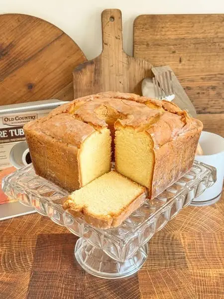 So far I've made two pound cakes using powdered sugar instead of granulated sugar and I can confidently say that it is SO much better! You must try this swap in your next pound cake! Mile High Cream Cheese Powdered Sugar Pound Cake  1 pound (4 sticks) butter, room temperature 7 cups powdered sugar, sifted if lumpy 1 1/2 packages (12 oz) cream cheese, room temperature 1 tablespoon vanilla extract 1 tablespoon lemon extract 1 teaspoon baking powder 1 teaspoon salt 8 large eggs, room temperature 4 1/2 cups cake flour or White Lily All Purpose Flour Preheat oven to 325°F. Prepare Old Country Kitchenware square tube pan by brushing with pan coat (if using two piece pan, fit with a parchment paper square between the two pieces first). Beat butter and sugar in the bowl of a stand mixer until pale, light and fluffy (about 6 minutes at medium speed). Add cream cheese, extracts, baking powder, salt, and 1/2 cup flour, beat until combined. With the mixer running on low, add one egg at a time, beating well after each addition until fully incorporated. Beat in the remaining flour in two additions, mixing until the flour just disappears. Scrape the bottom and sides of the bowl and beat for another 10 seconds. Pour batter into prepared tube pan and gently shake to settle the batter. Place on middle rack of oven with a baking sheet on the rack below it to catch any drips. Bake 1 hour 55 minutes or until a skewer inserted into the cake comes out clean. Let cool until the pan is comfortable enough to handle. (If using two-piece pan, place it over a metal can and press down to remove the outer piece first). Transfer the cake to a wire rack in two steps: first, turn the cake up on its side, then invert fully. Let cool completely. Crackly Donut Glaze 1 cup powdered sugar 3-5 tablespoons milk, water, or lemon juice Beat together powdered sugar and liquid until smooth and runny. Drizzle over cake and use a pastry brush to evenly distribute over the sides. Wait for glaze to harden before serving (about 20 minutes).