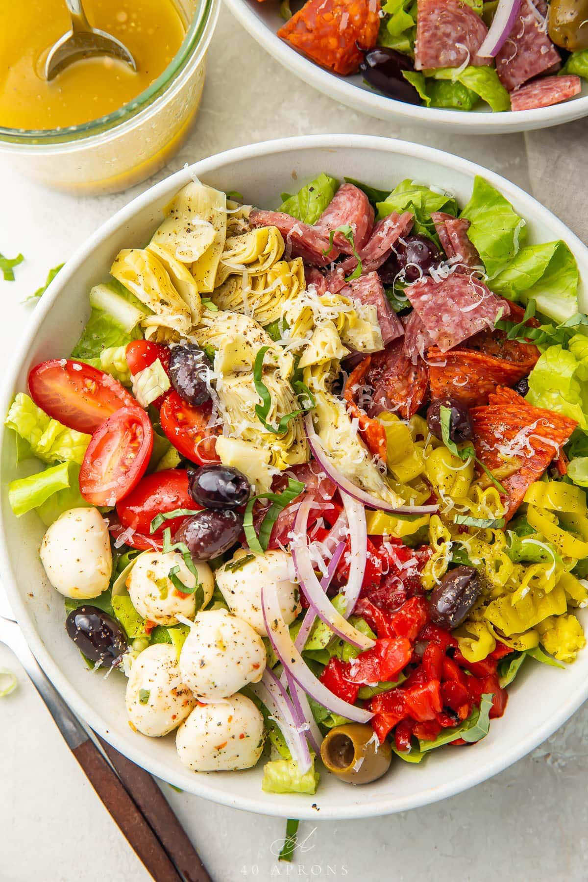 This delicious antipasto salad features all your Italian antipasto favorites in a refreshing, flavorful salad.  With plenty of salami, prosciutto, and pepperoni, plus mozzarella balls, tomatoes, olives, roasted red peppers, pepperoncini, and red onion, tossed in a quick and easy Italian vinaigrette. #NoCookMeals #ItalianFoodLover #SaladGoals #AntipastoVibes #WeeknightDinnerWin