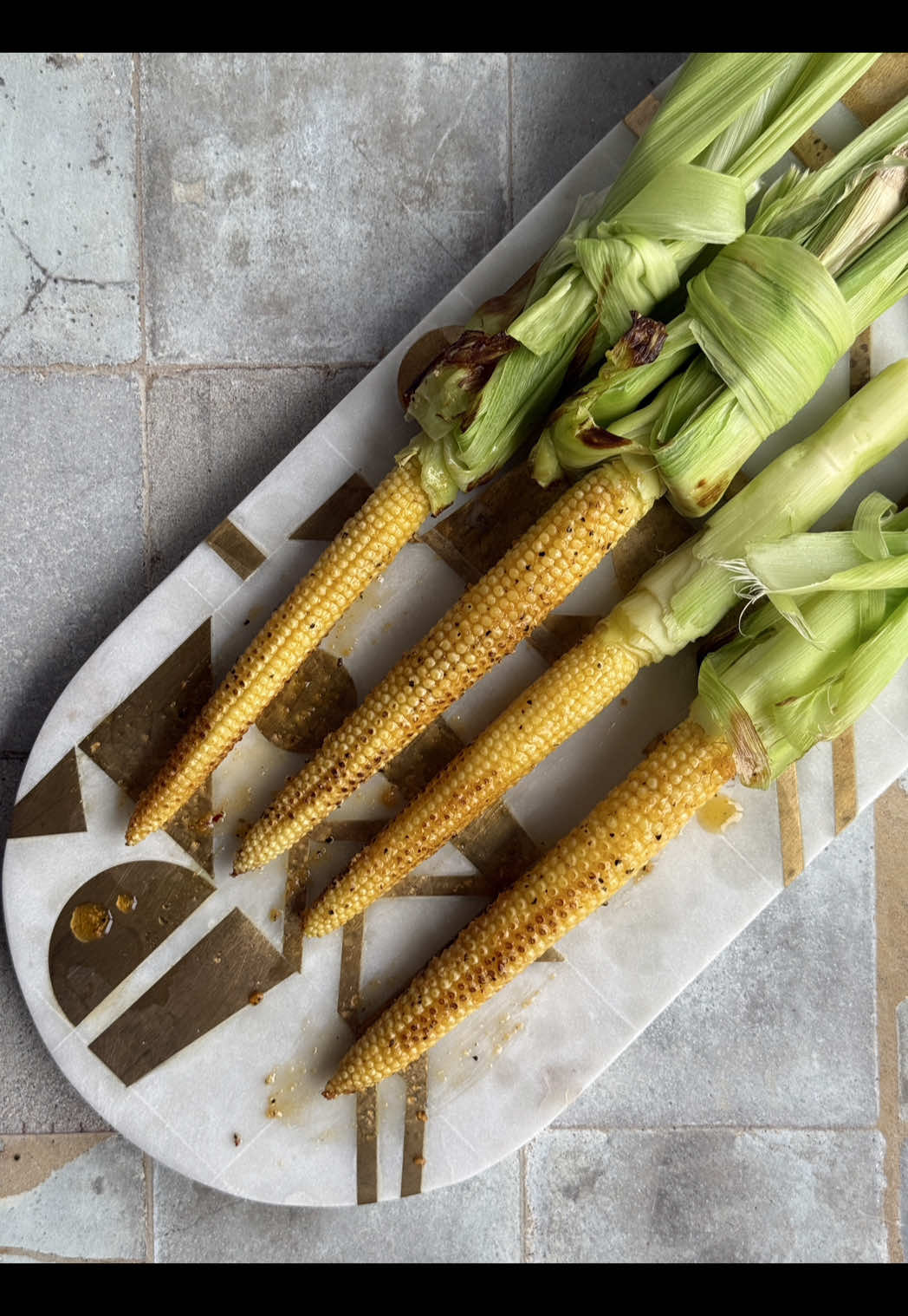 Found these at my local farmer’s market, grilled them for that perfect smoky char, and brushed on flavored butter. 10/10 summer snack vibes 🌽✨  Here’s how to make it: 1. Carefully peel the husk and fold in down, keep it intact by tying another piece of husk around or using a string. Alternatively, use canned whole baby corn 2. Grill the baby corn on a cast iron with a little bit of olive oil, just until all sides are evenly browned 3. In a bowl, mix melted butter, salt, and preferred seasonings. I used @Osmo Kitchen new Garden Harvest Blend (Thank you Osmo and Nick for the gift!) 4. Brush the grilled baby corn with the flavored butter and enjoy fresh!