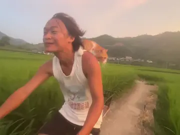 Pure healing vibes: a young man rides his bike at dusk, a kitten calmly perched on his back, with green rice fields and a pastel-pink sky in the backdrop. It looks straight out of an animated film. #GreenChina #EcoChina #Chinalife #petlovers #cat